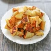 a piled of roasted golden potatoes on a white plate