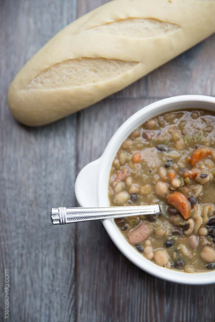 a white bowl filled with soup with a french bread baguette in the background