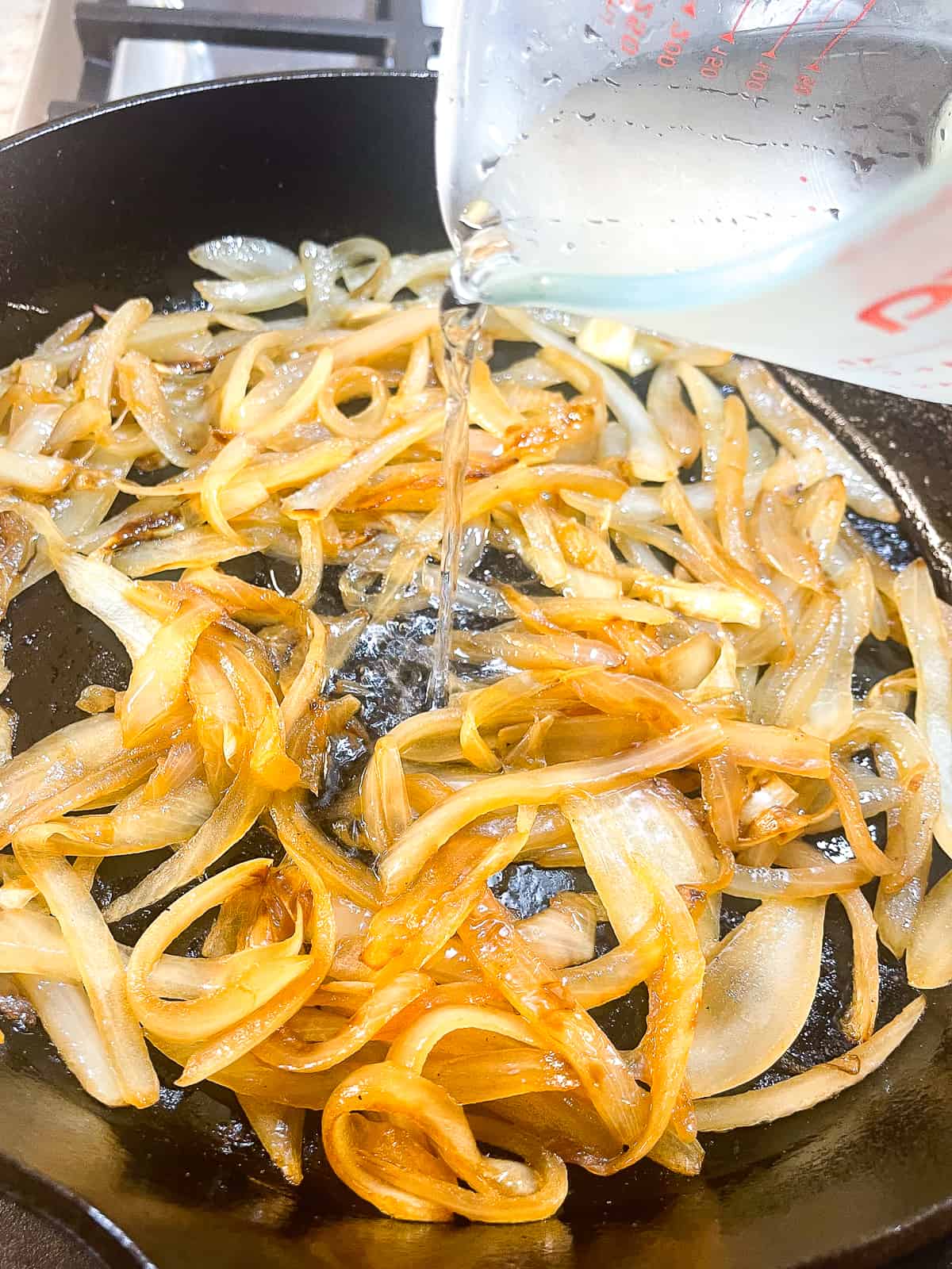 pouring water into the pan while sauteeing onions