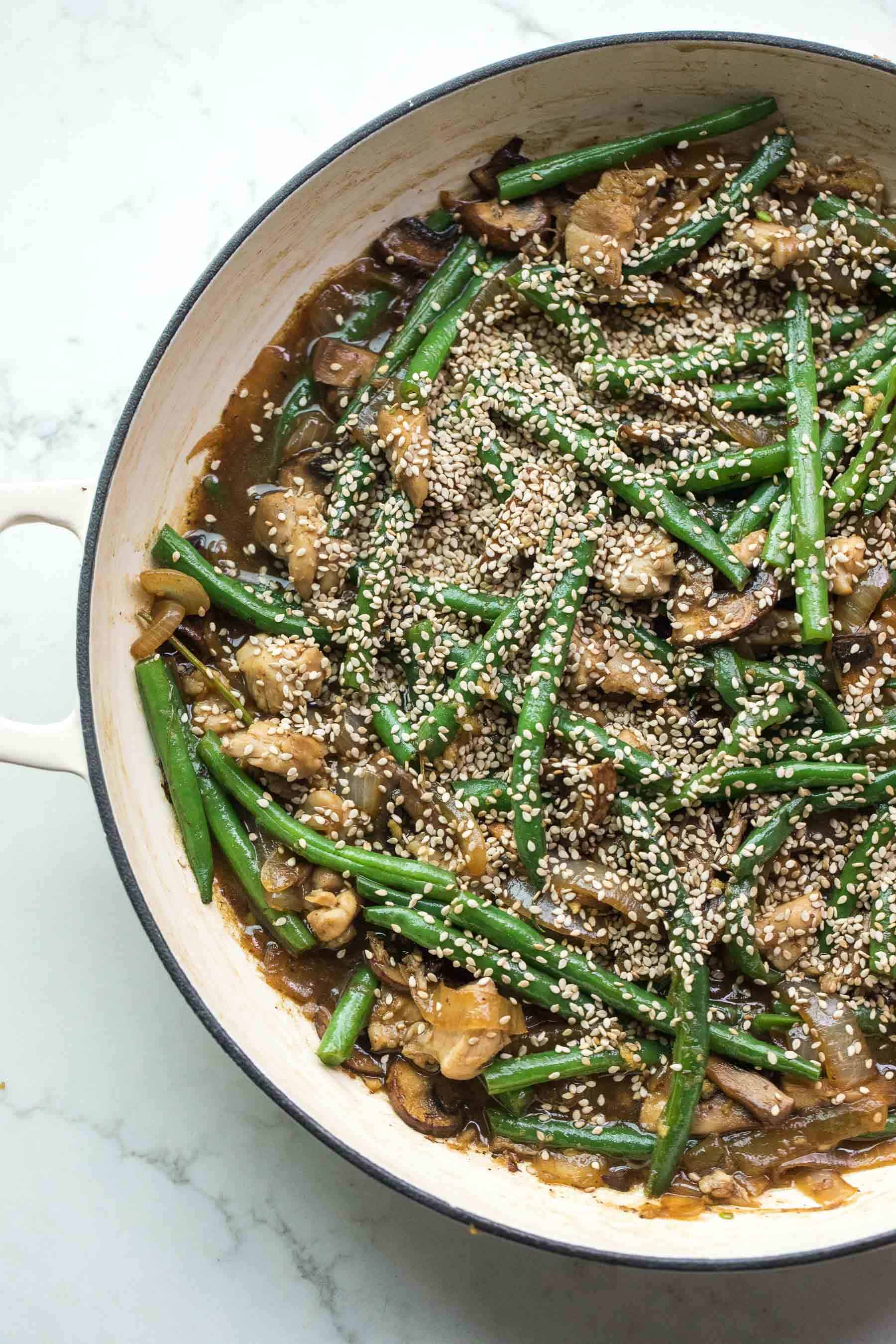 sesame chicken green bean stir fry in a white pan