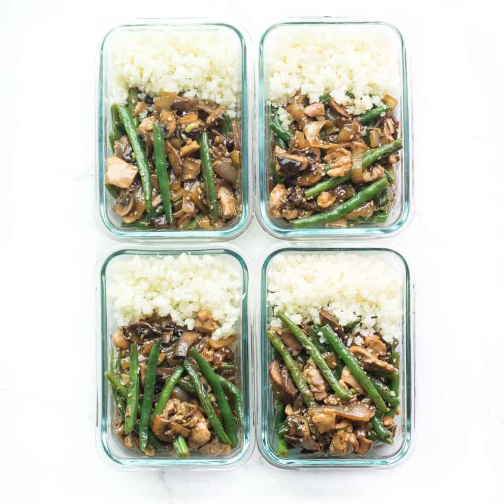 meal prep containers holding sesame chicken green bean stir fry