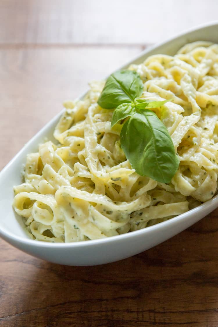 creamy pesto pasta in a white bowl