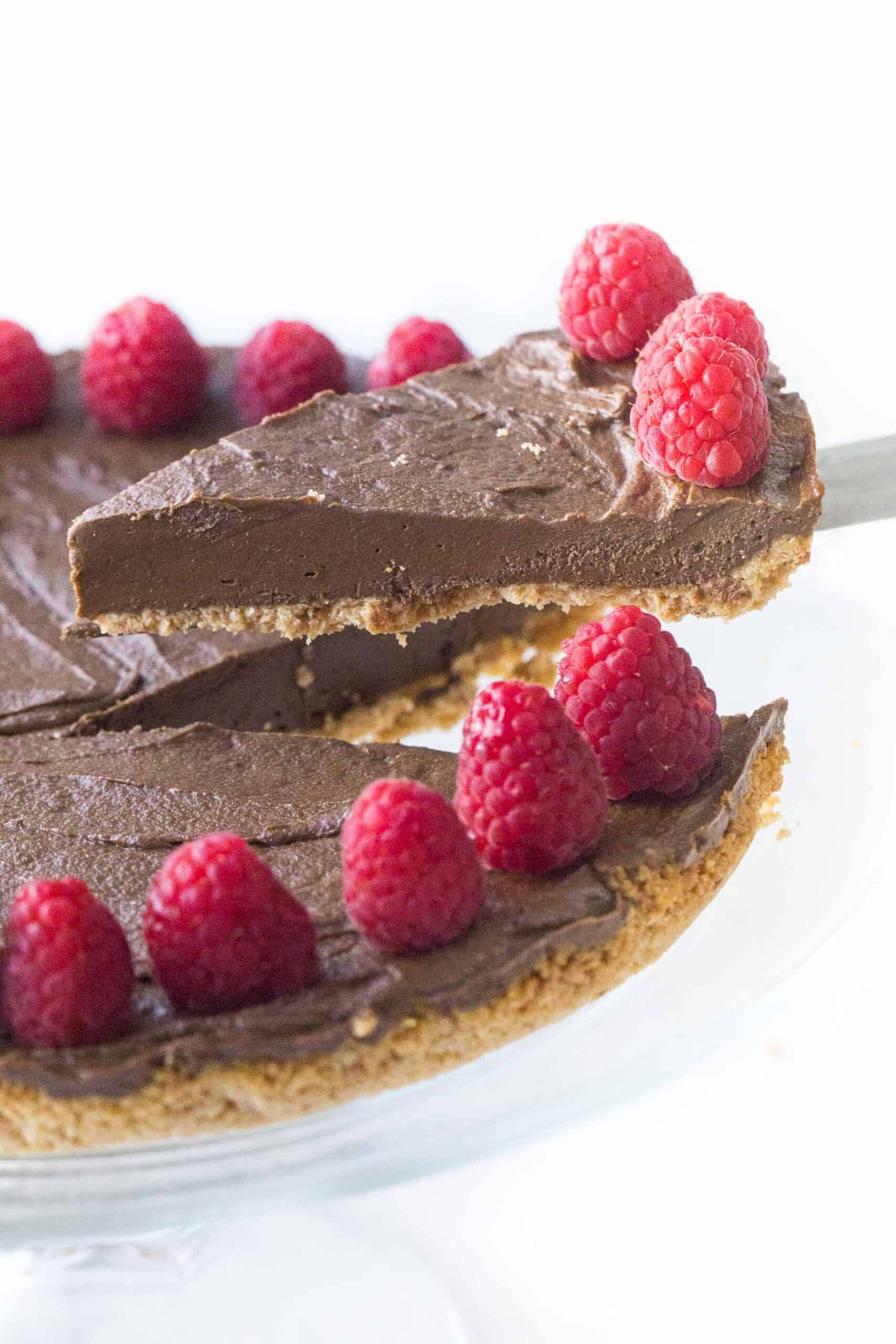 lifting a slice of healthy chocolate tart with raspberries