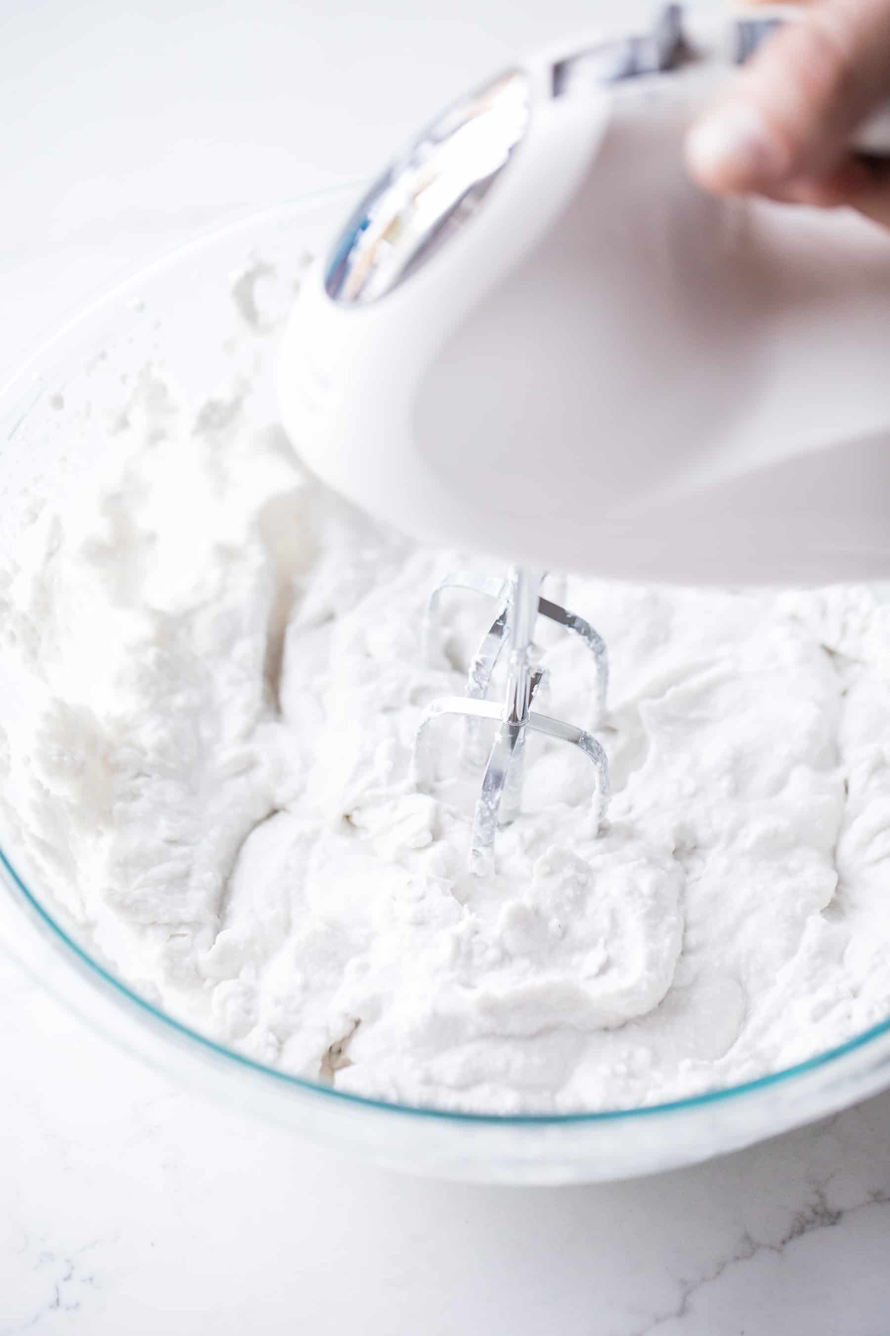 Hand mixer beating coconut whipped cream