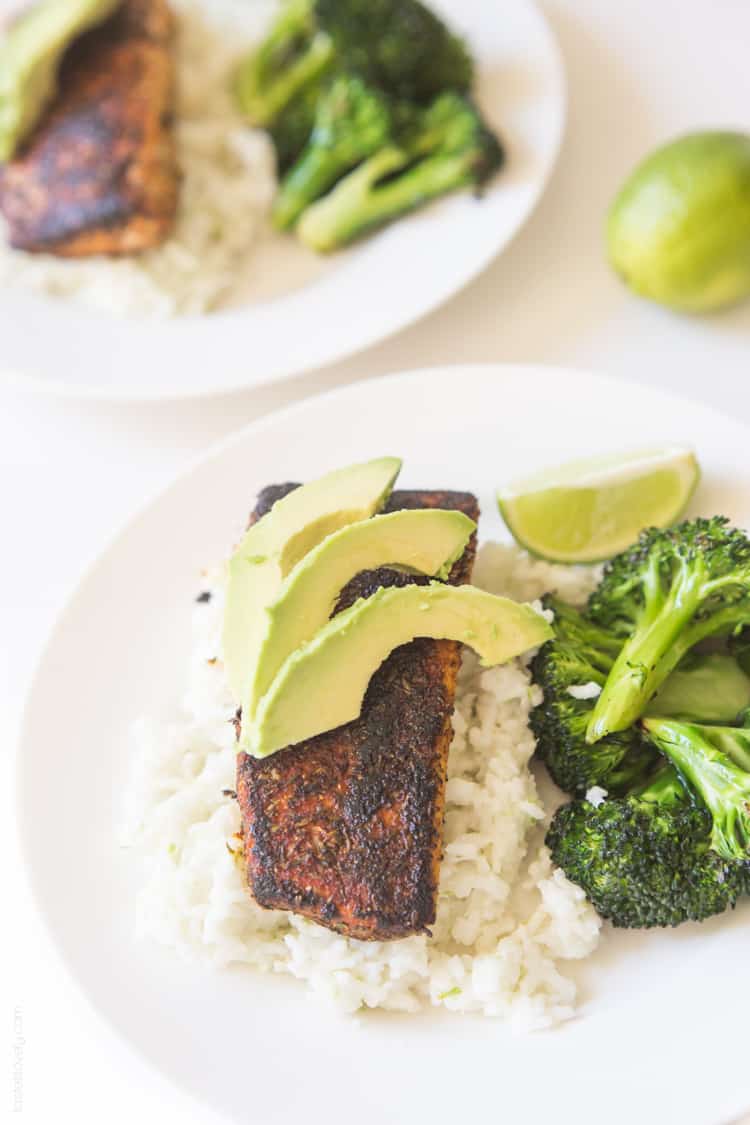 an overhead shot of a blackened Mahi Mahi fillet on a bed of rice topped with avocado next to broccoli florets and a lime wedge. 