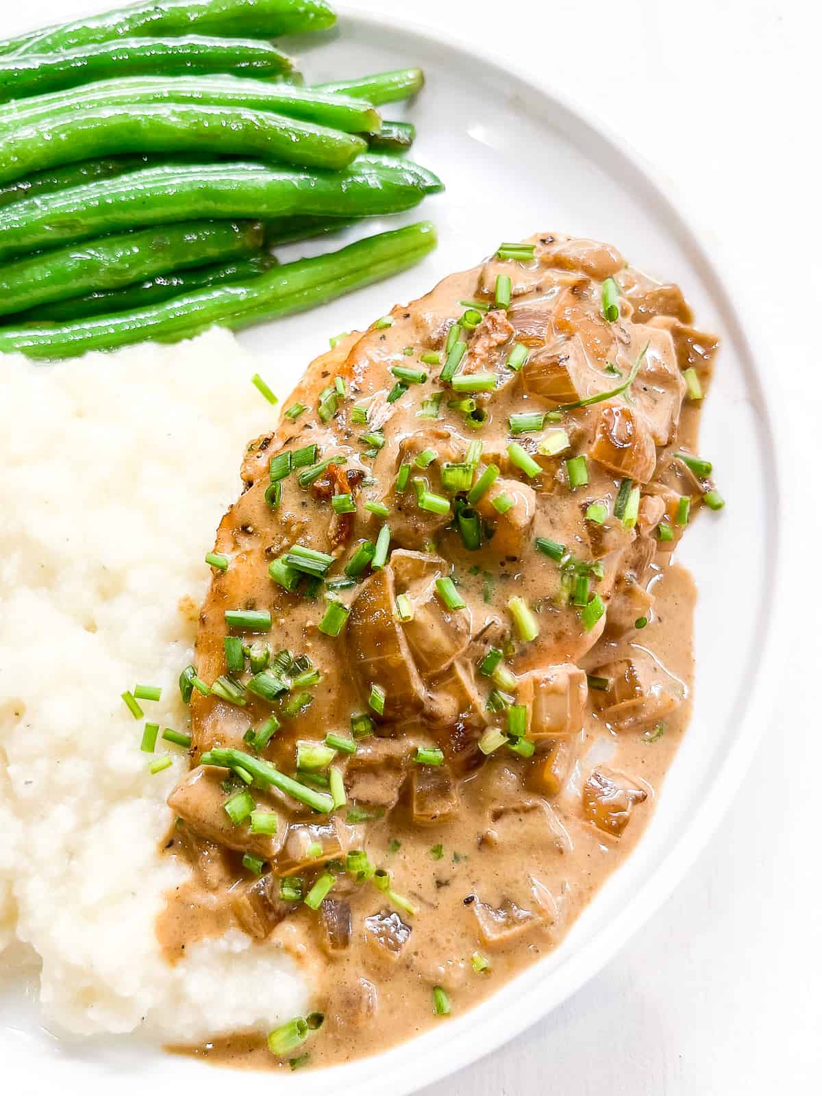 chicken with dijon mustard sauce on a white plate with green beans and mashed potatoes 