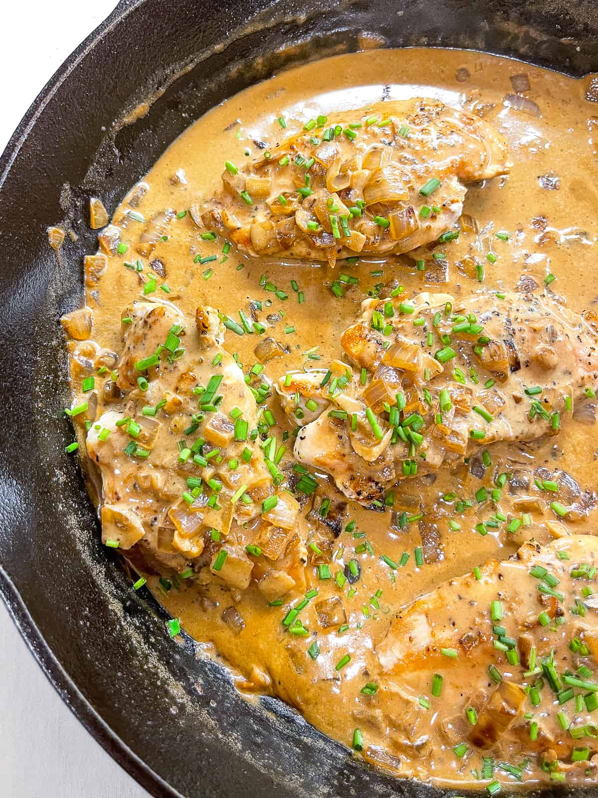 chicken with mustard sauce cooking in a cast iron skillet