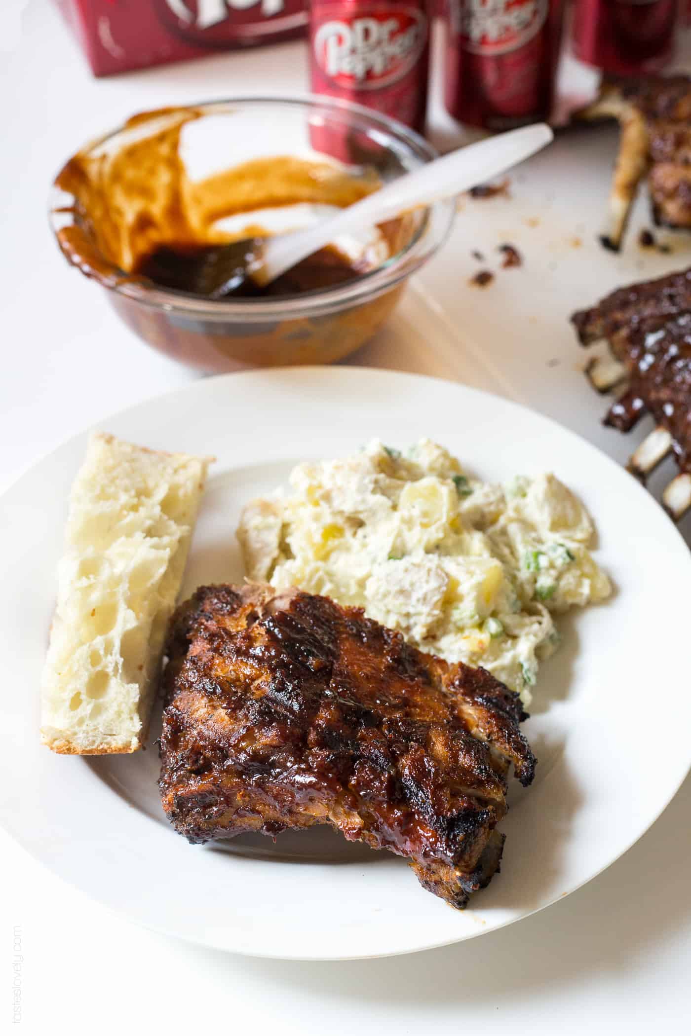 dr pepper ribs on a white plate with potato salad and bread