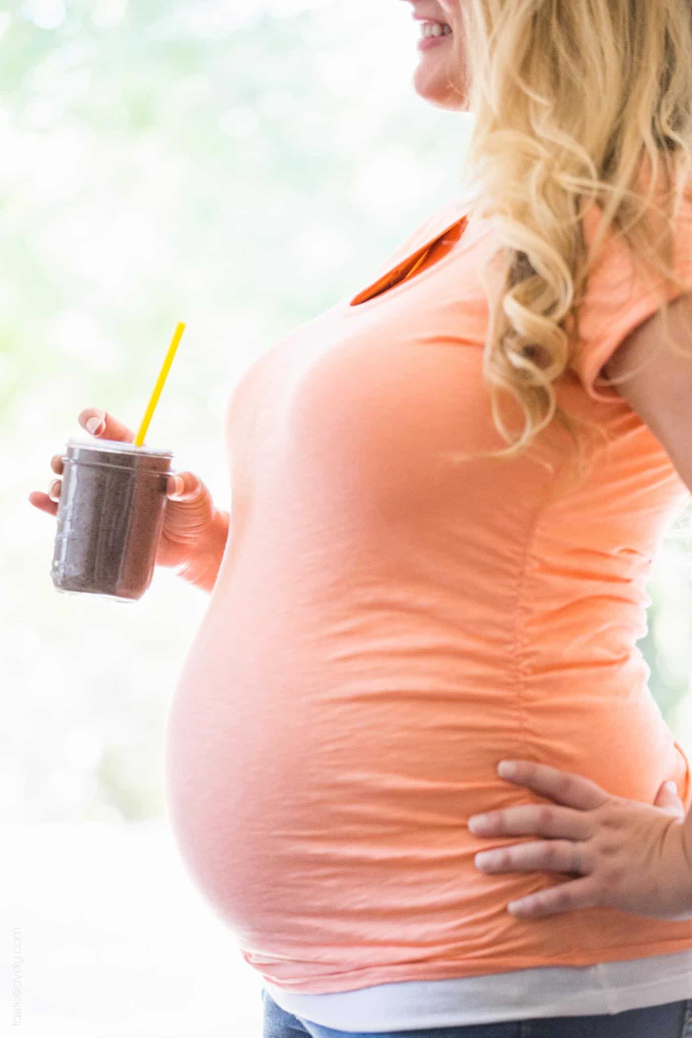 pregnant woman holding a glass with a yellow straw