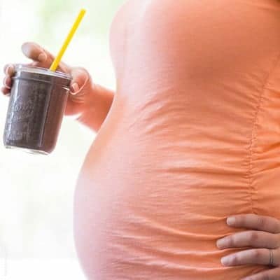 pregnant woman holding a homemade smoothie
