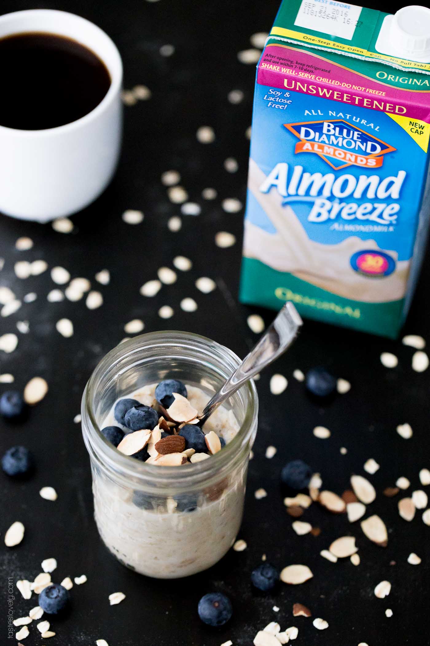 oatmeal in a glass mason jar next to a container of unsweetened almond milk and a cup of coffee