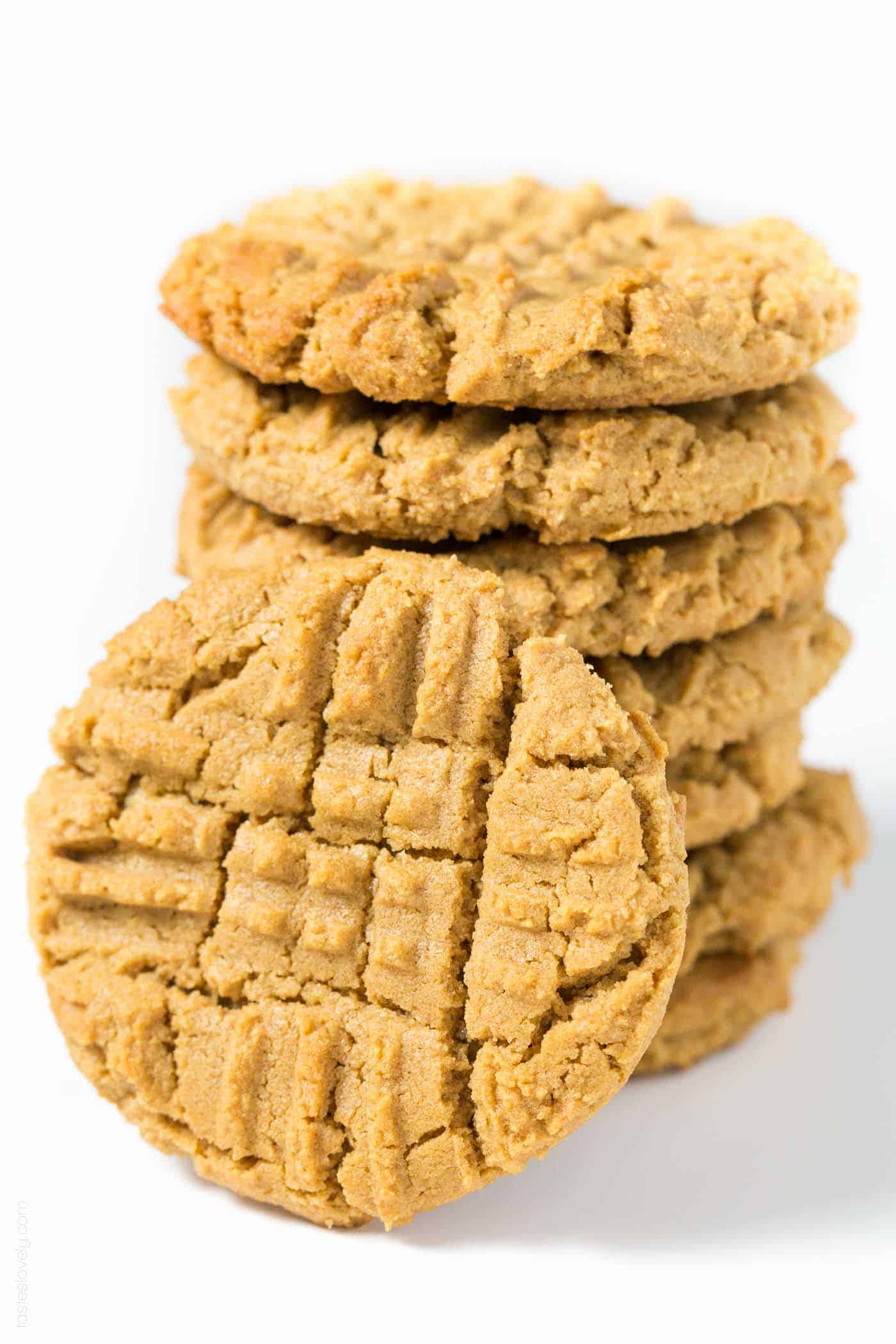 a stack of gluten-free peanut butter cookies with one resting against the front of the stack. 