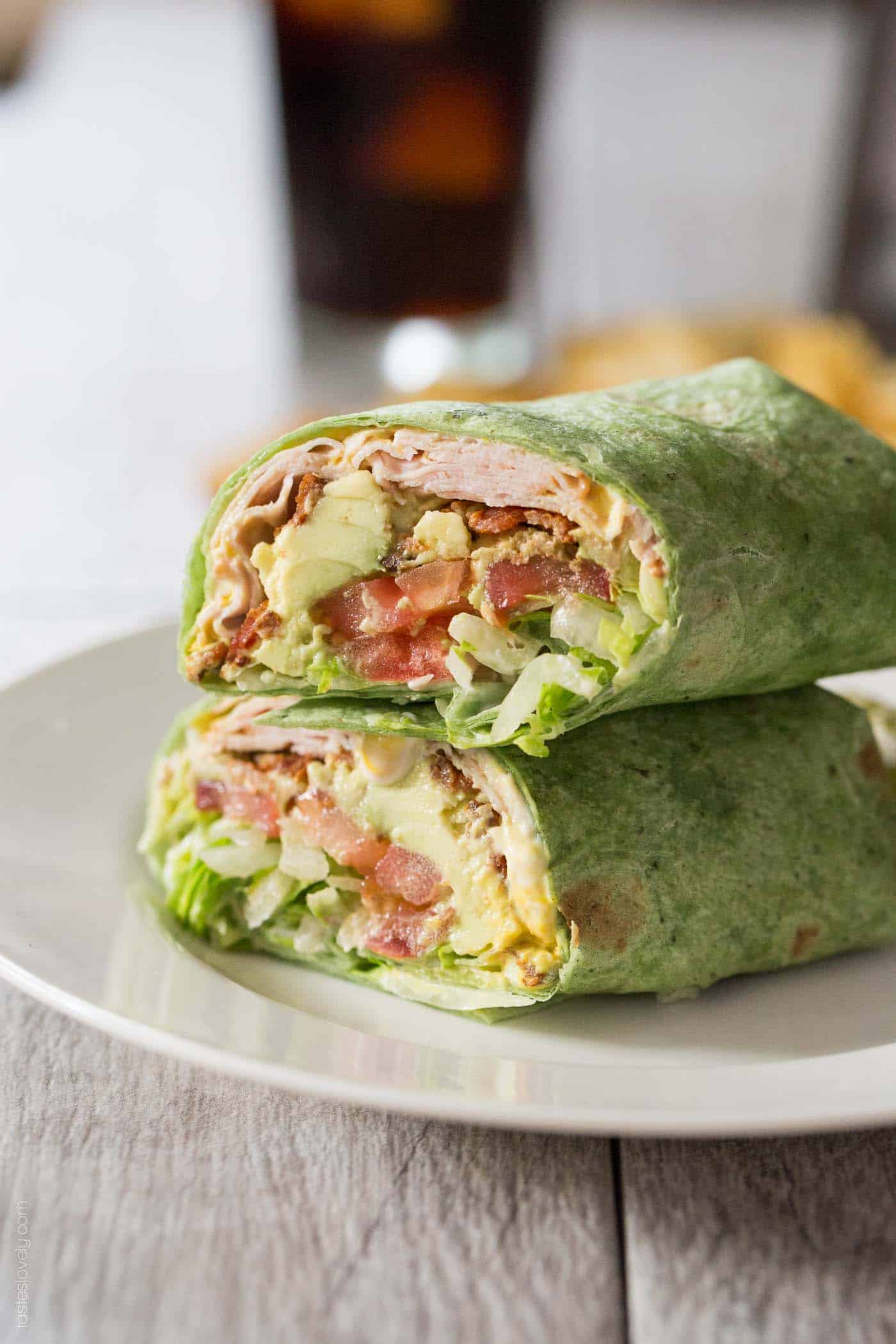 turkey, bacon, avocado, and tomato wrapped in a spinach tortilla and stacked on top of another wrap