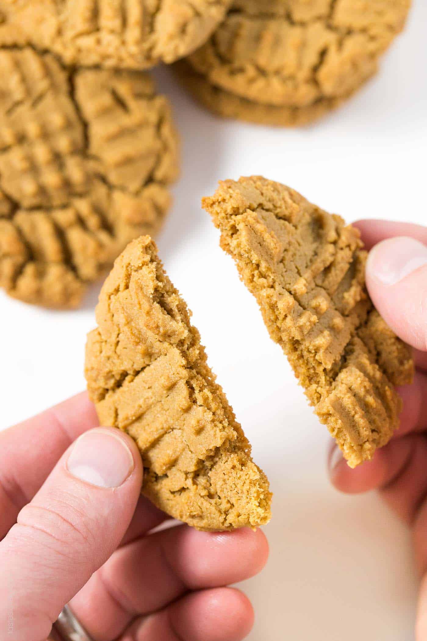 a hand breaking a cookie in half