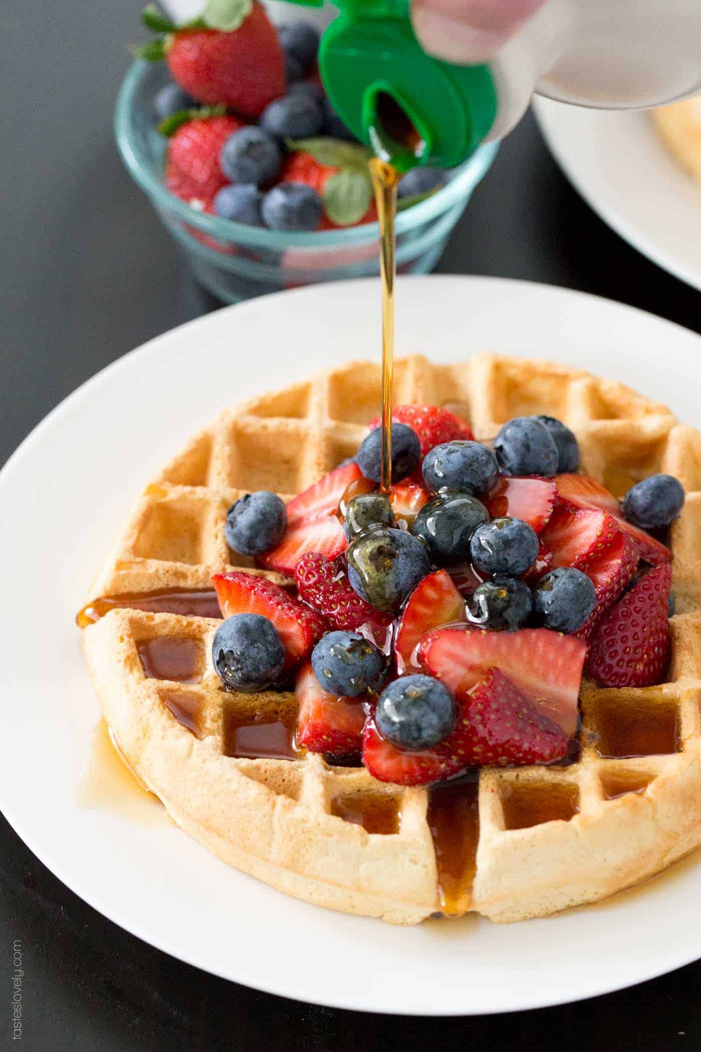 syrup pouring over dairy free waffles with fresh berries