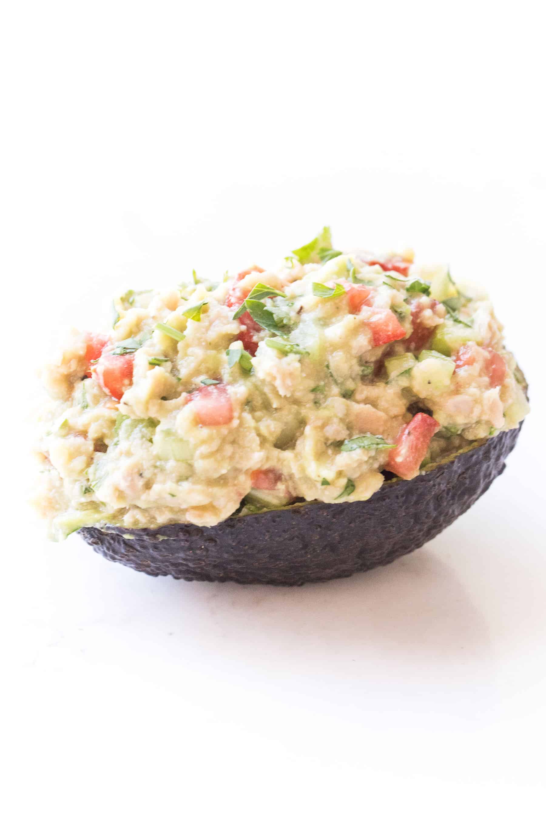 Avocado tuna salad in an avocado boat skin on a white background
