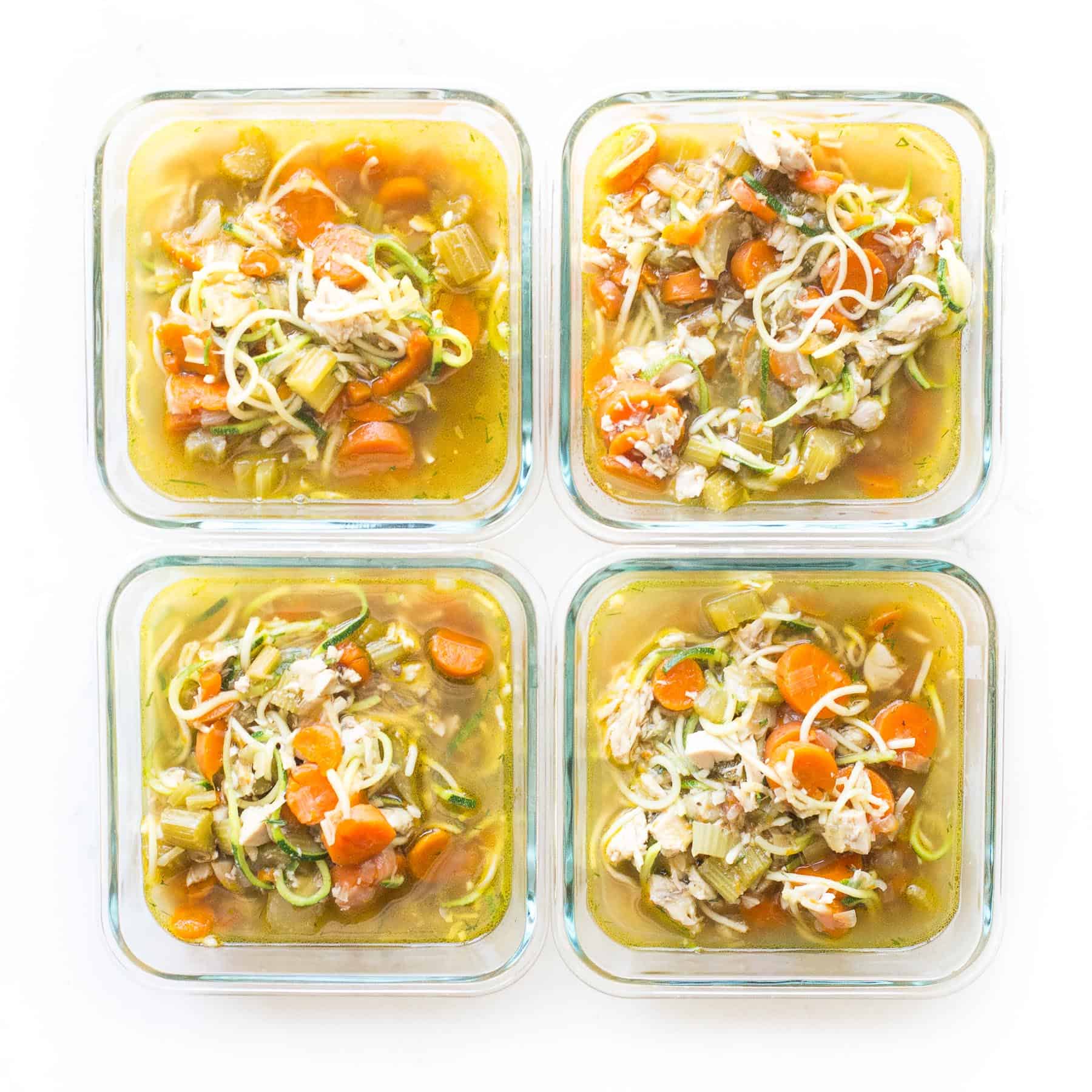 chicken zoodle soup in meal prep containers on a white background