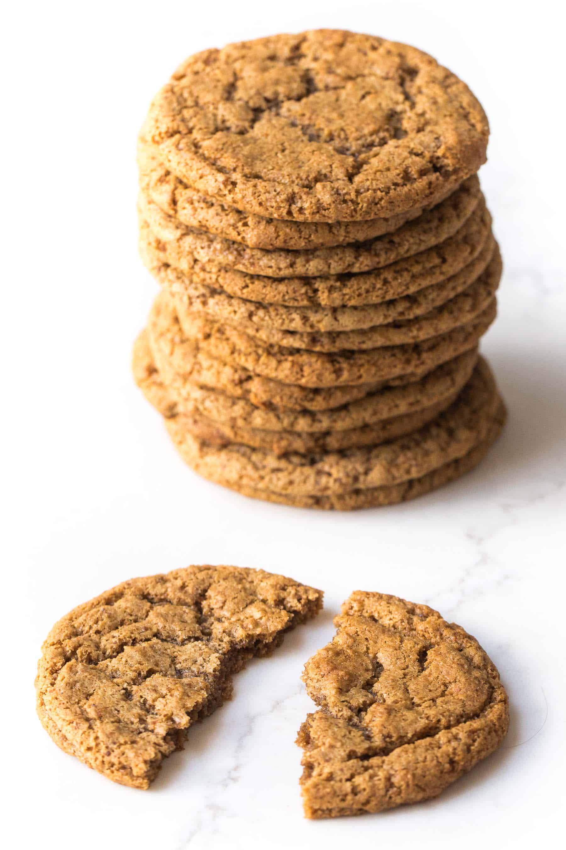 stack of almond butter cookies and 1 cracked cookie on a white background