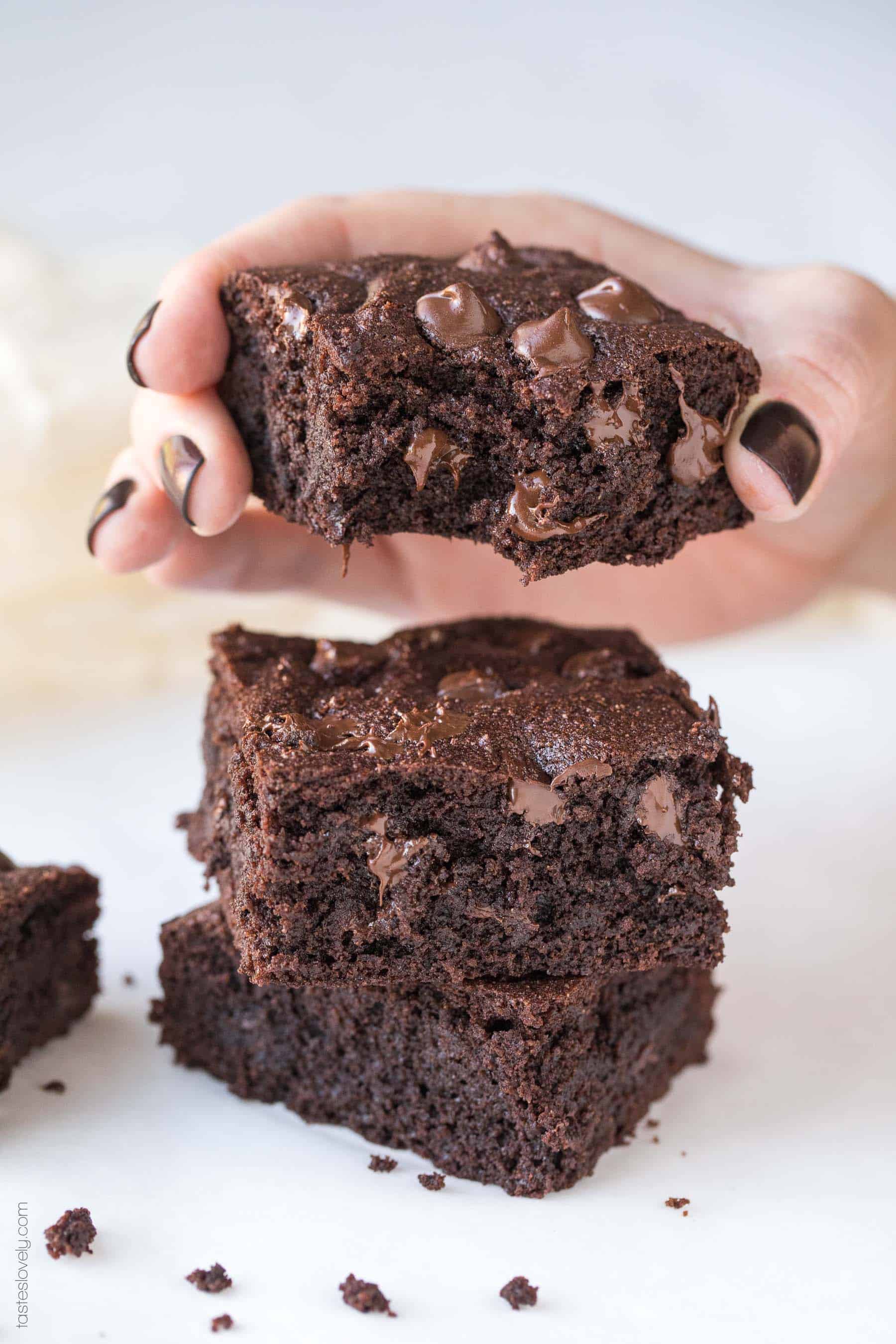 a hand holding a low carb, fudgy chocolate brownies with gooey chocolate chips with a bite taken out