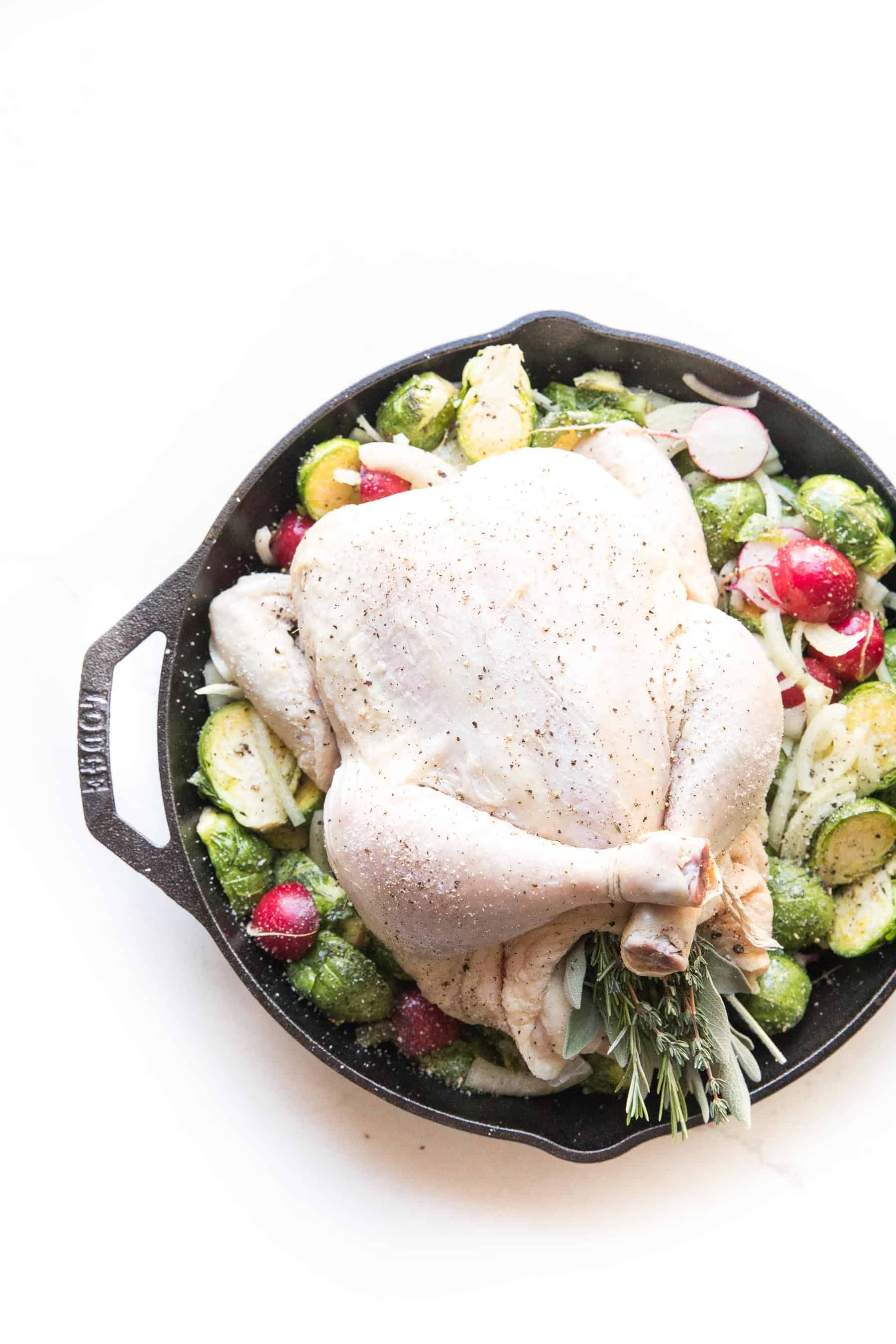 Whole30 + keto perfect roast chicken in a cast iron skillet with root vegetables