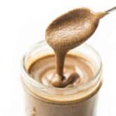 a spoon drizzling pecan butter into a mason jar