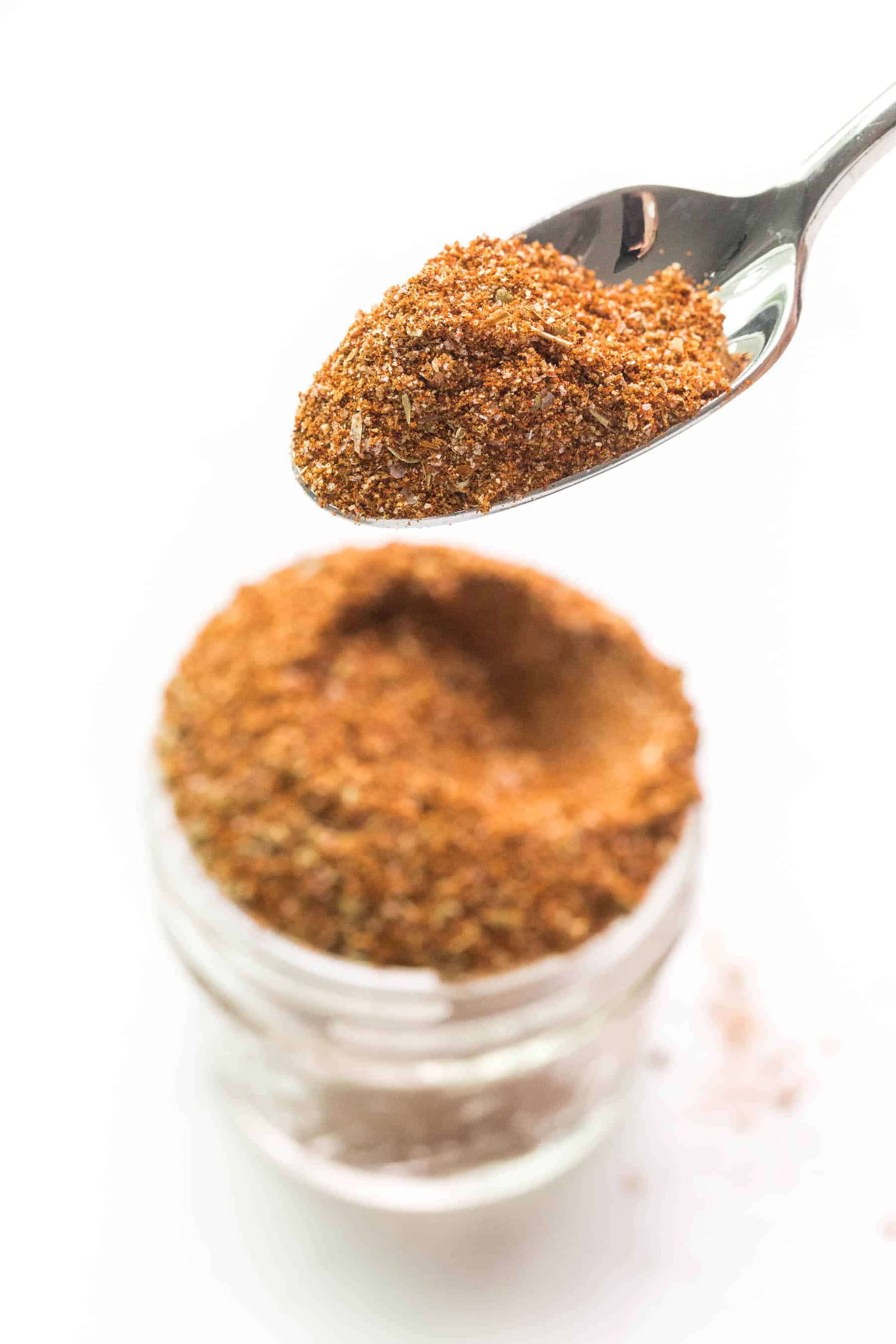 spoon holding taco seasoning on a white background