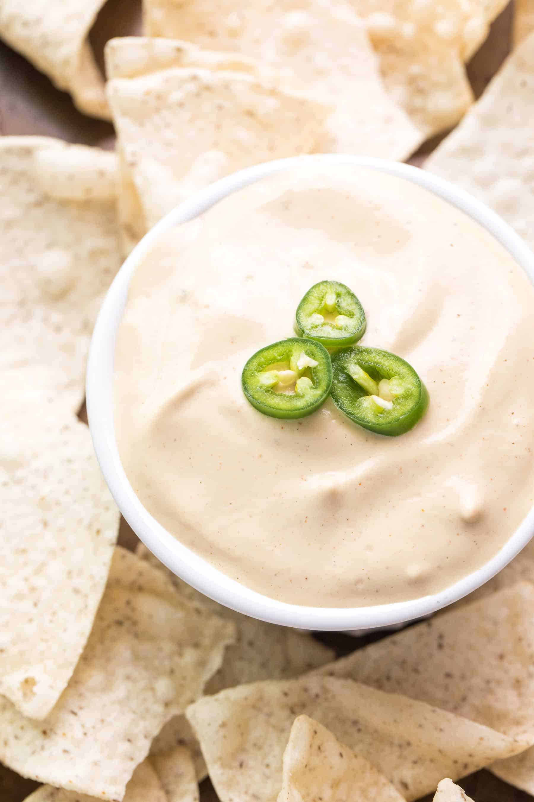 queso nacho cheese in a white bowl surrounded by tortilla chips