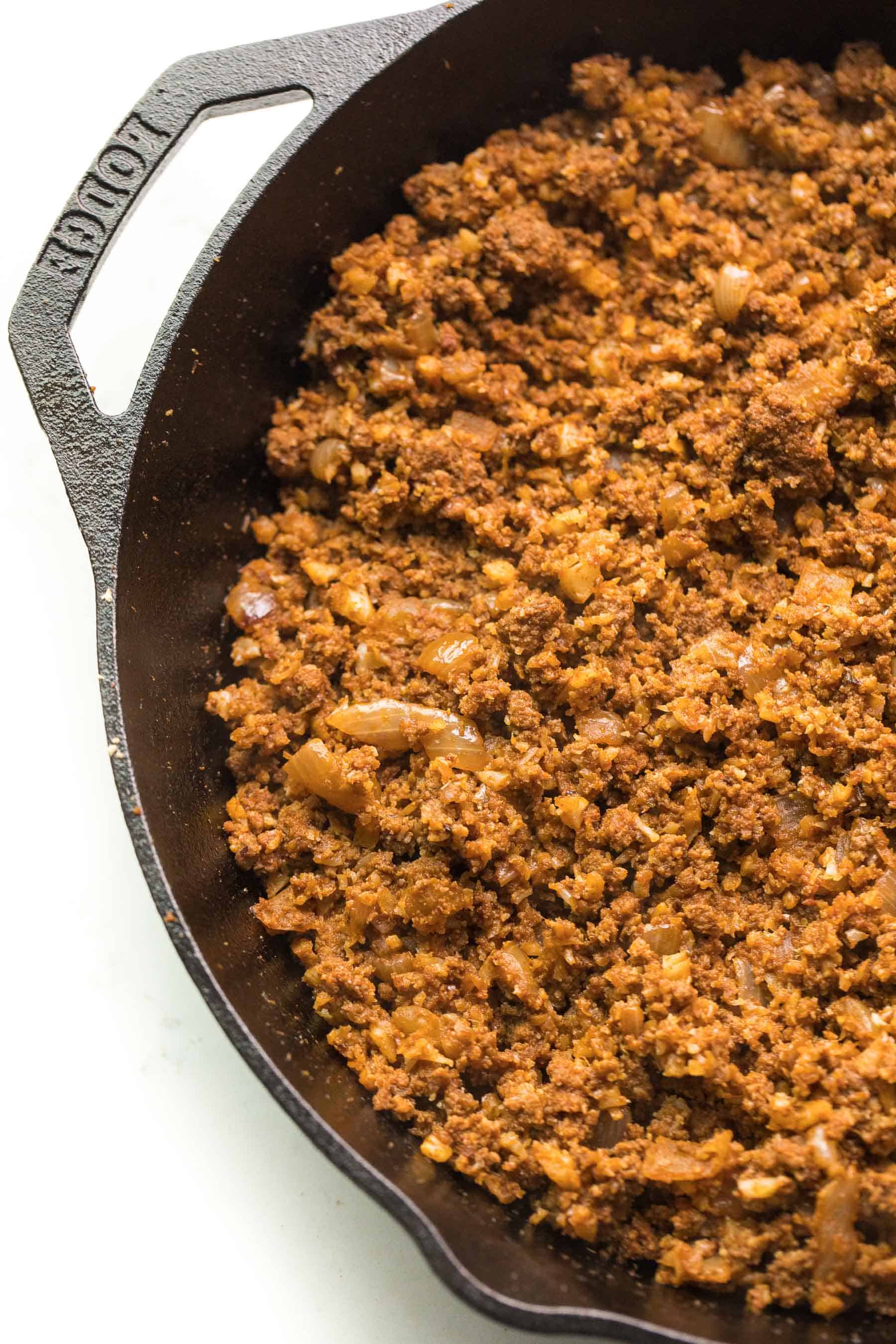 ground beef taco meat in a cast iron skillet on a white background