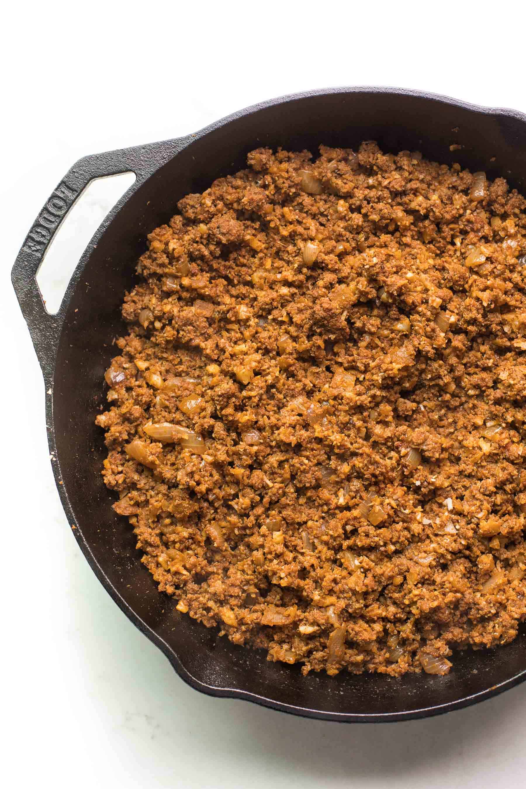 ground beef taco meat in a cast iron skillet on a white background