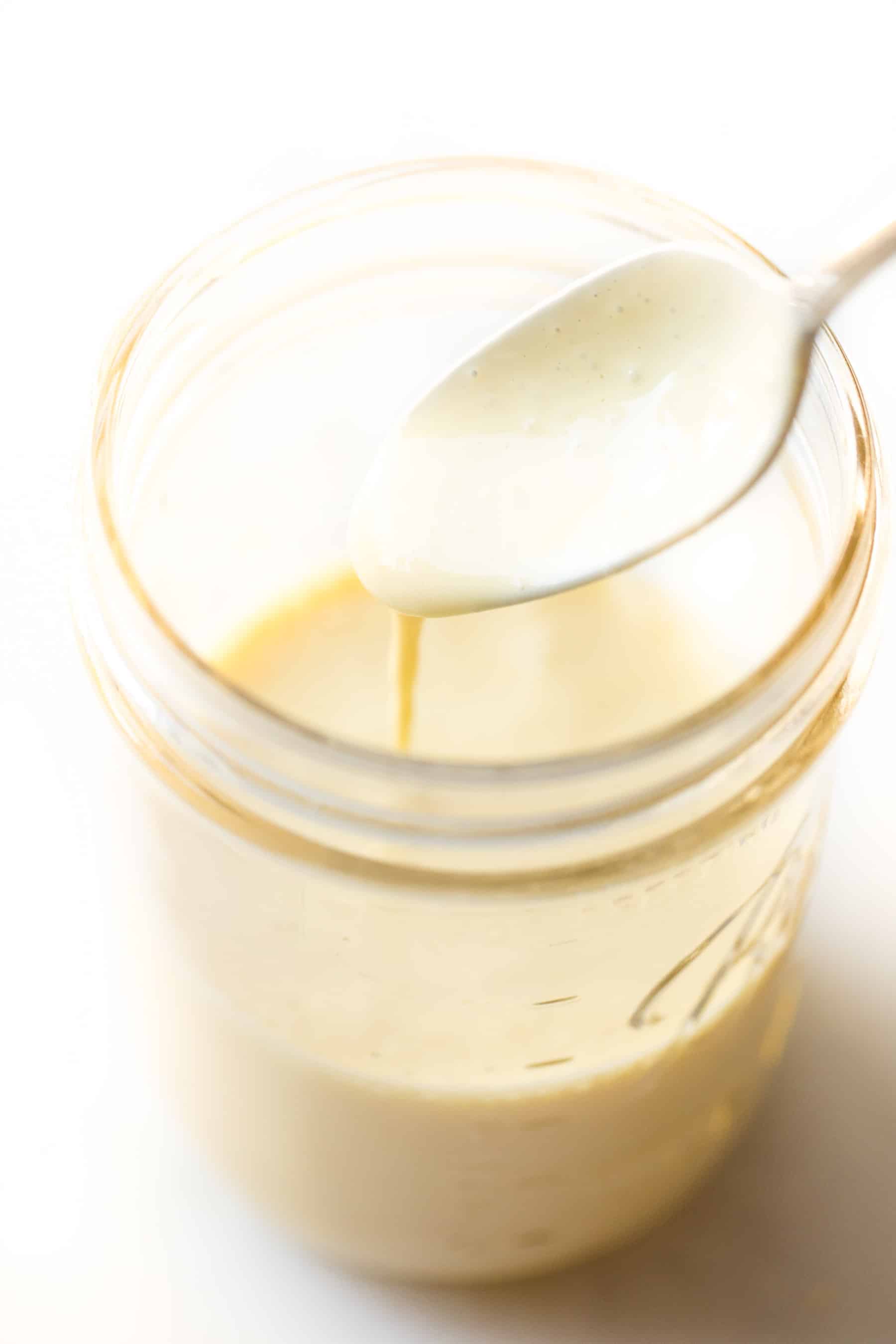 Spoon pouring hollandaise sauce in a mason jar