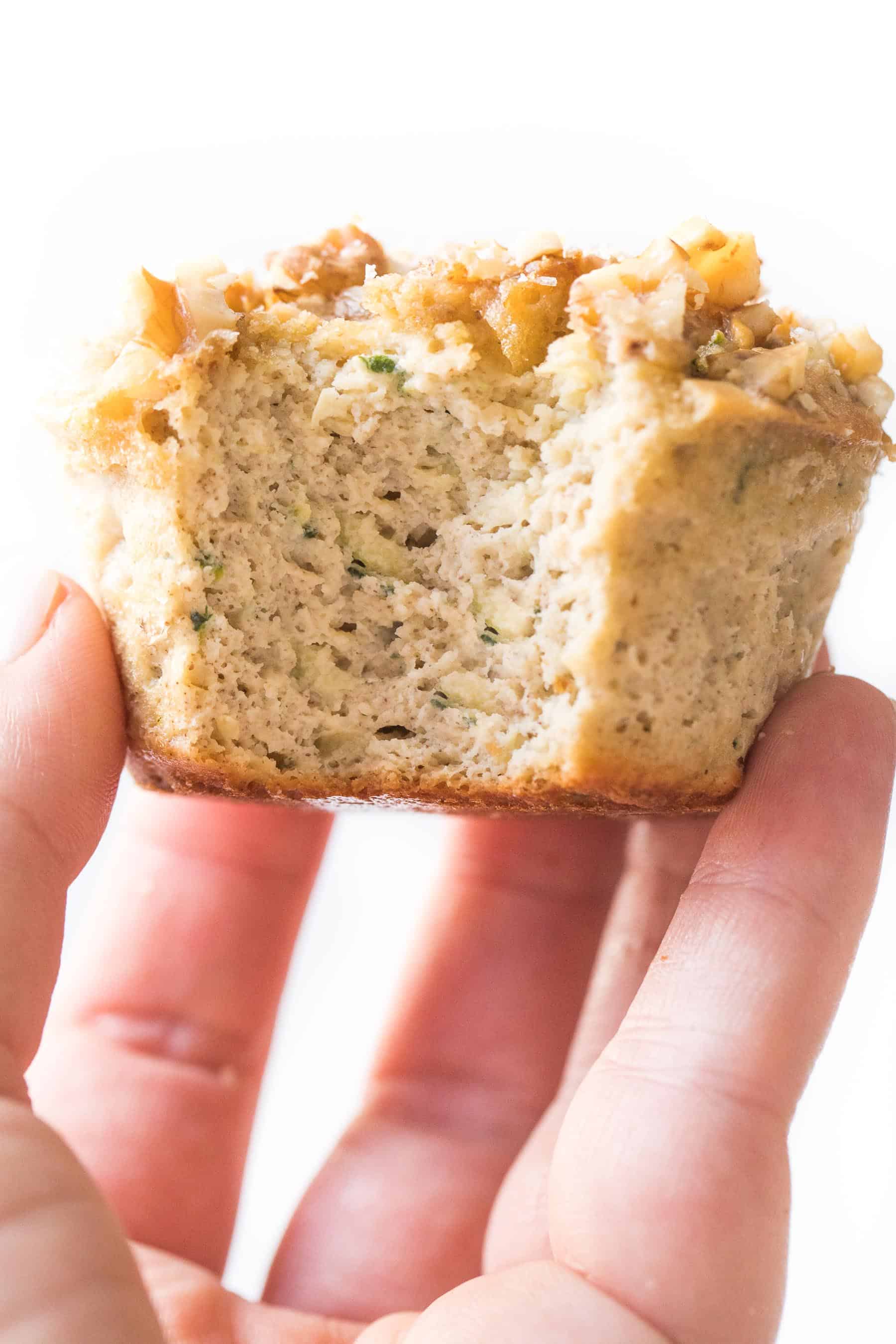 hand holding a paleo zucchini muffin on a white background