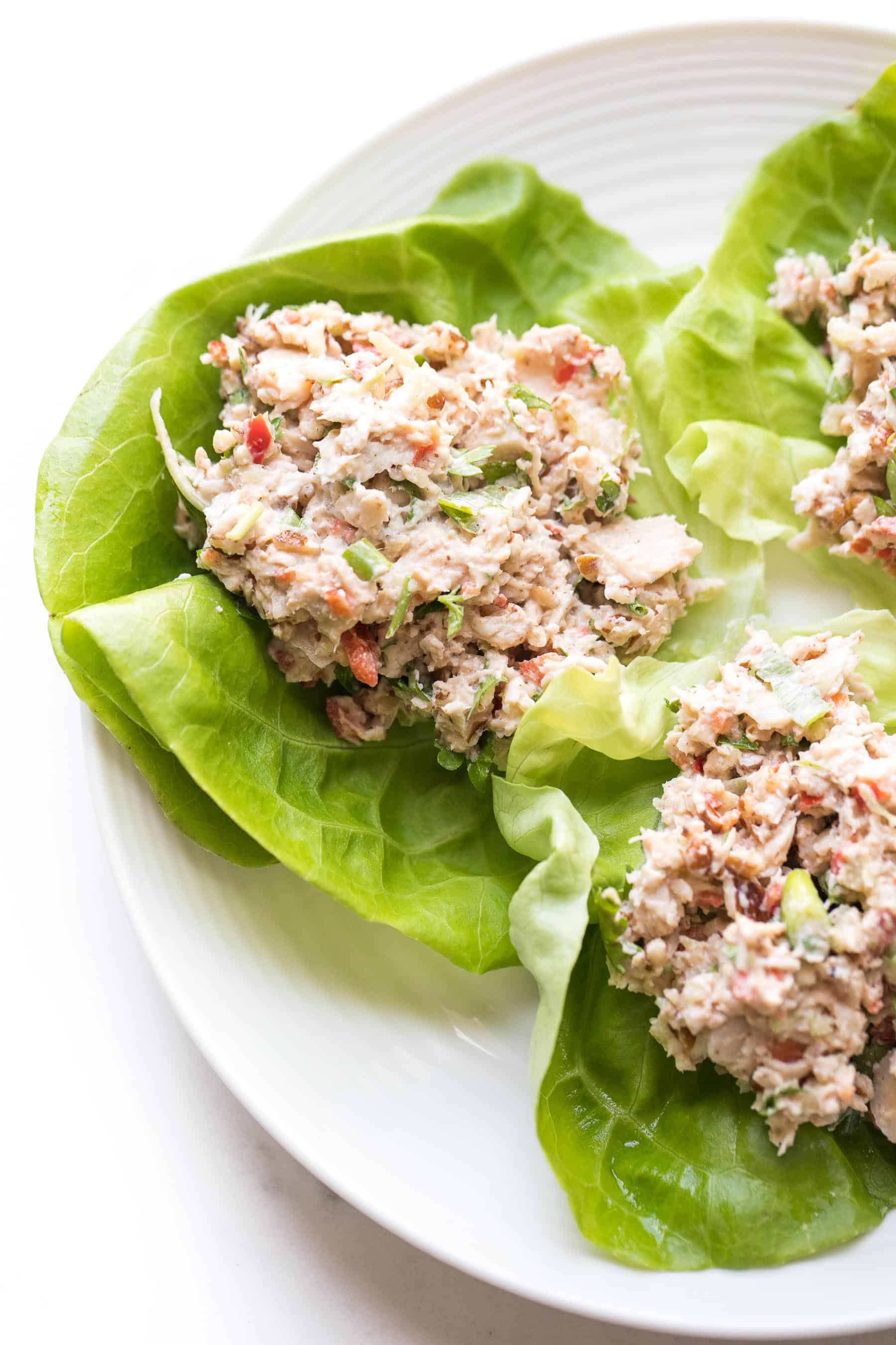 chicken salad on butter lettuce on a white plate and white background