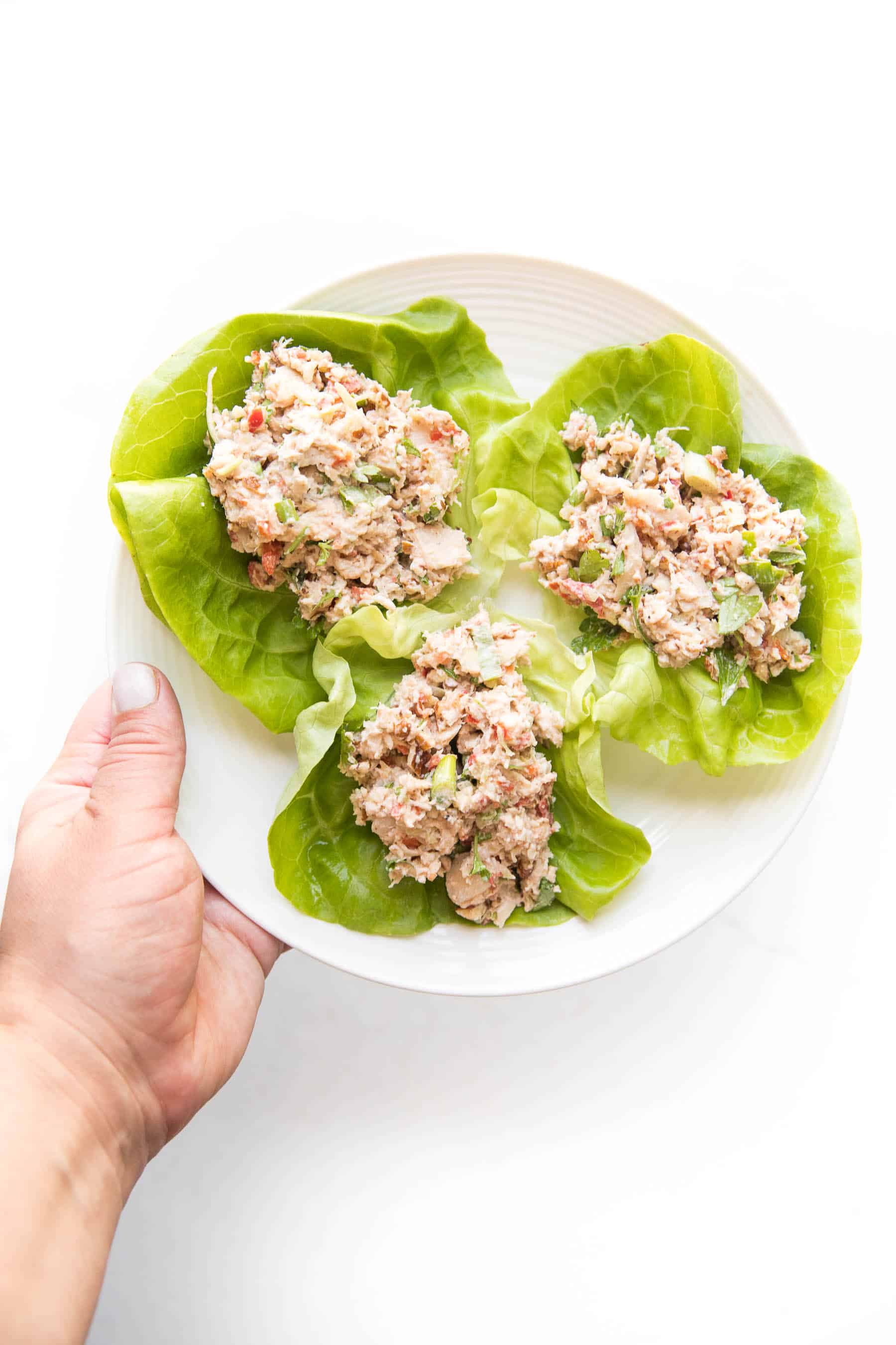 chicken salad on butter lettuce on a white plate and white background