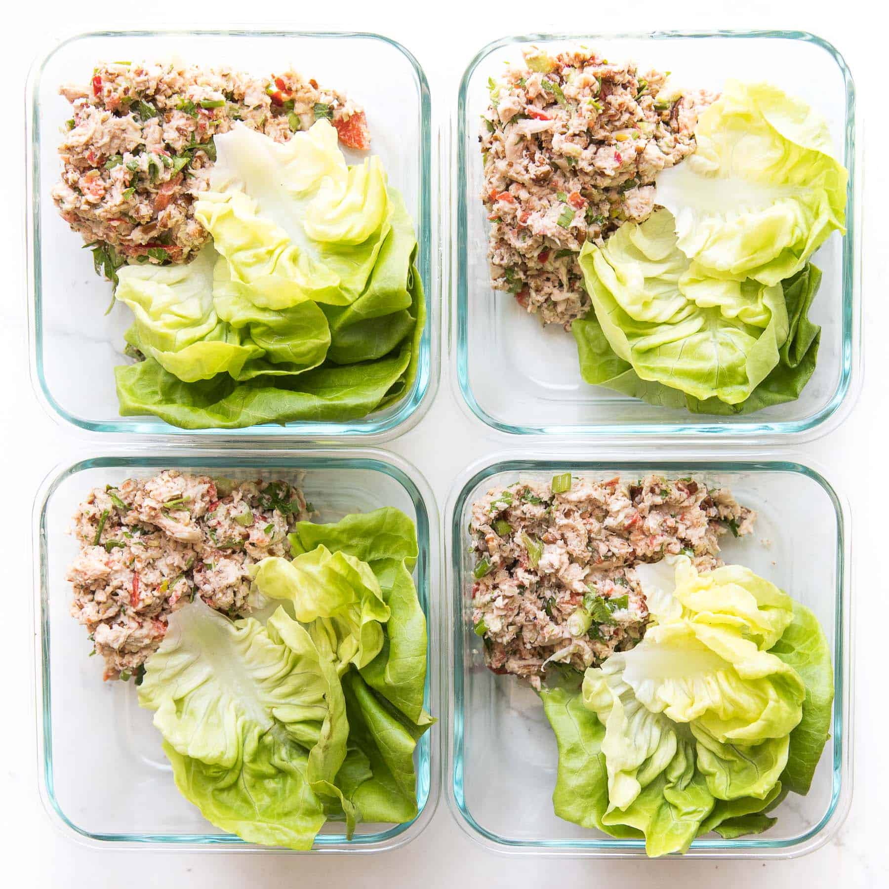 chicken salad and butter lettuce in meal prep containers on a white background