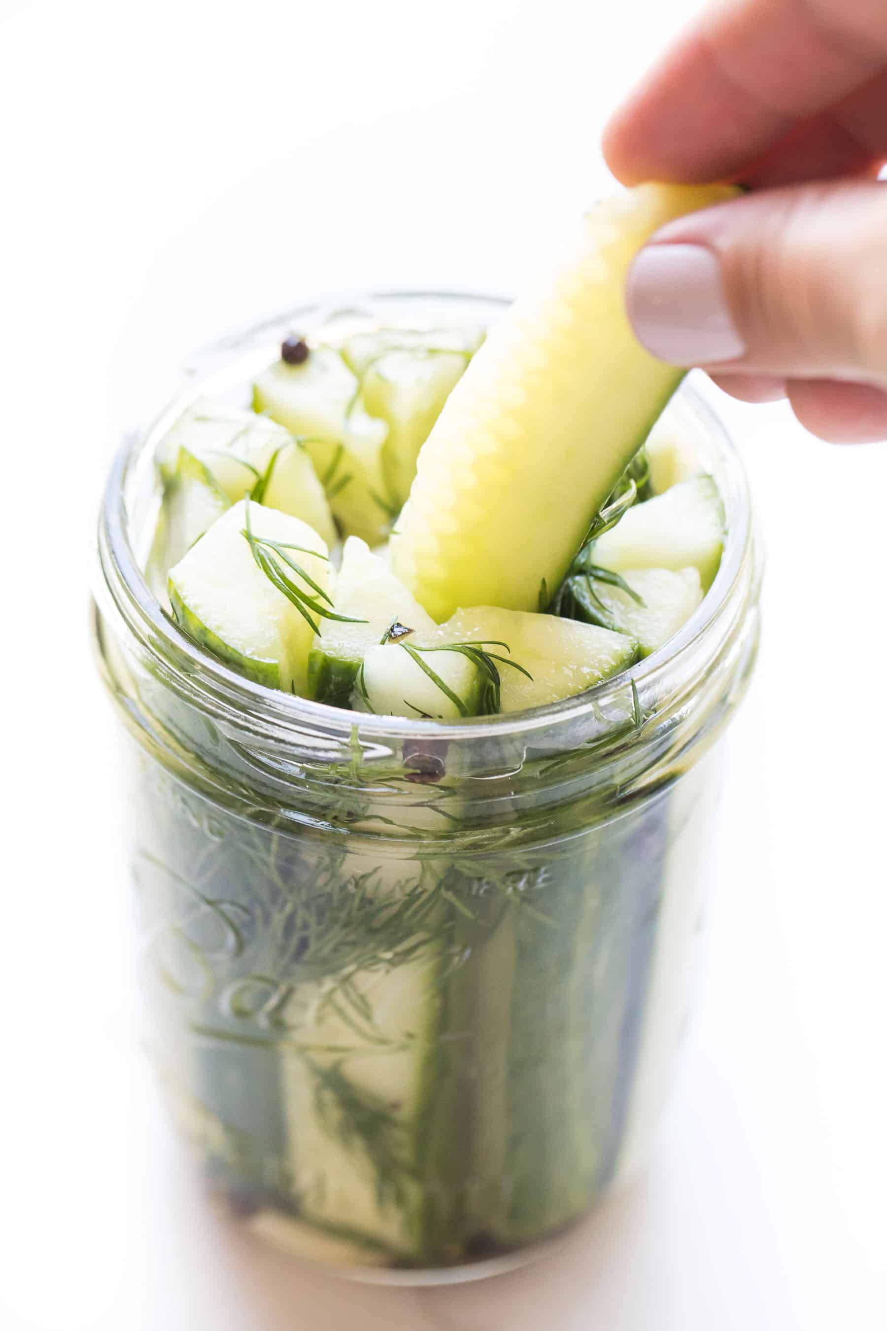 hand grabbing a pickle out of a mason jar