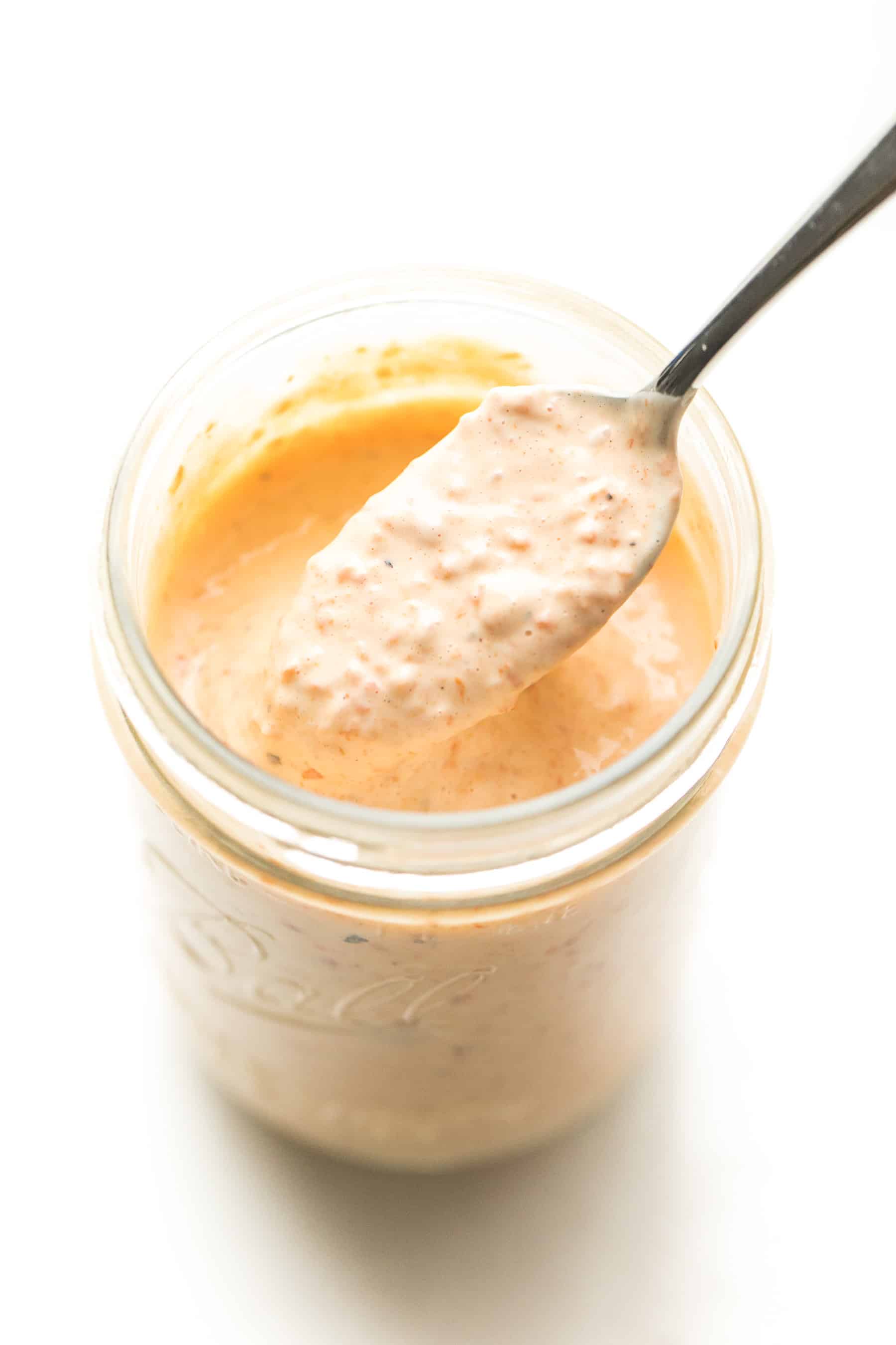 Spoon scooping out red pepper mayonnaise from a mason jar