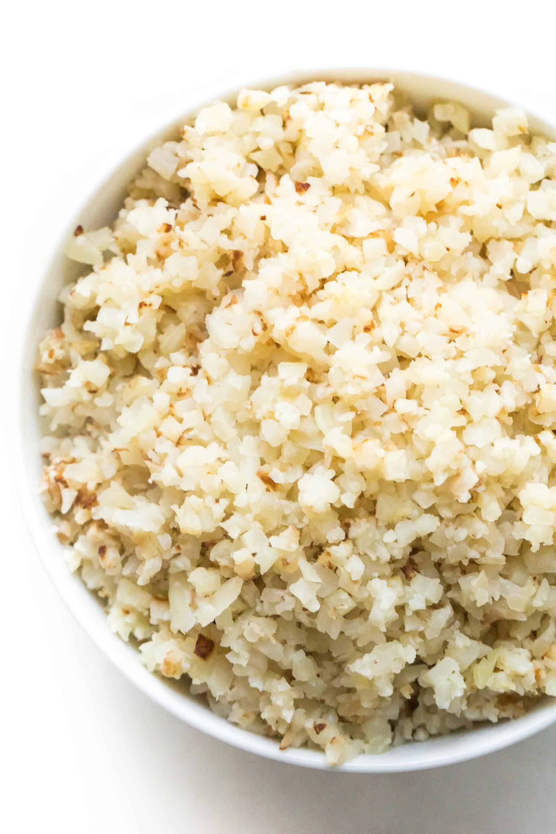 cauliflower rice after cooking it from frozen in a white bowl with a white background