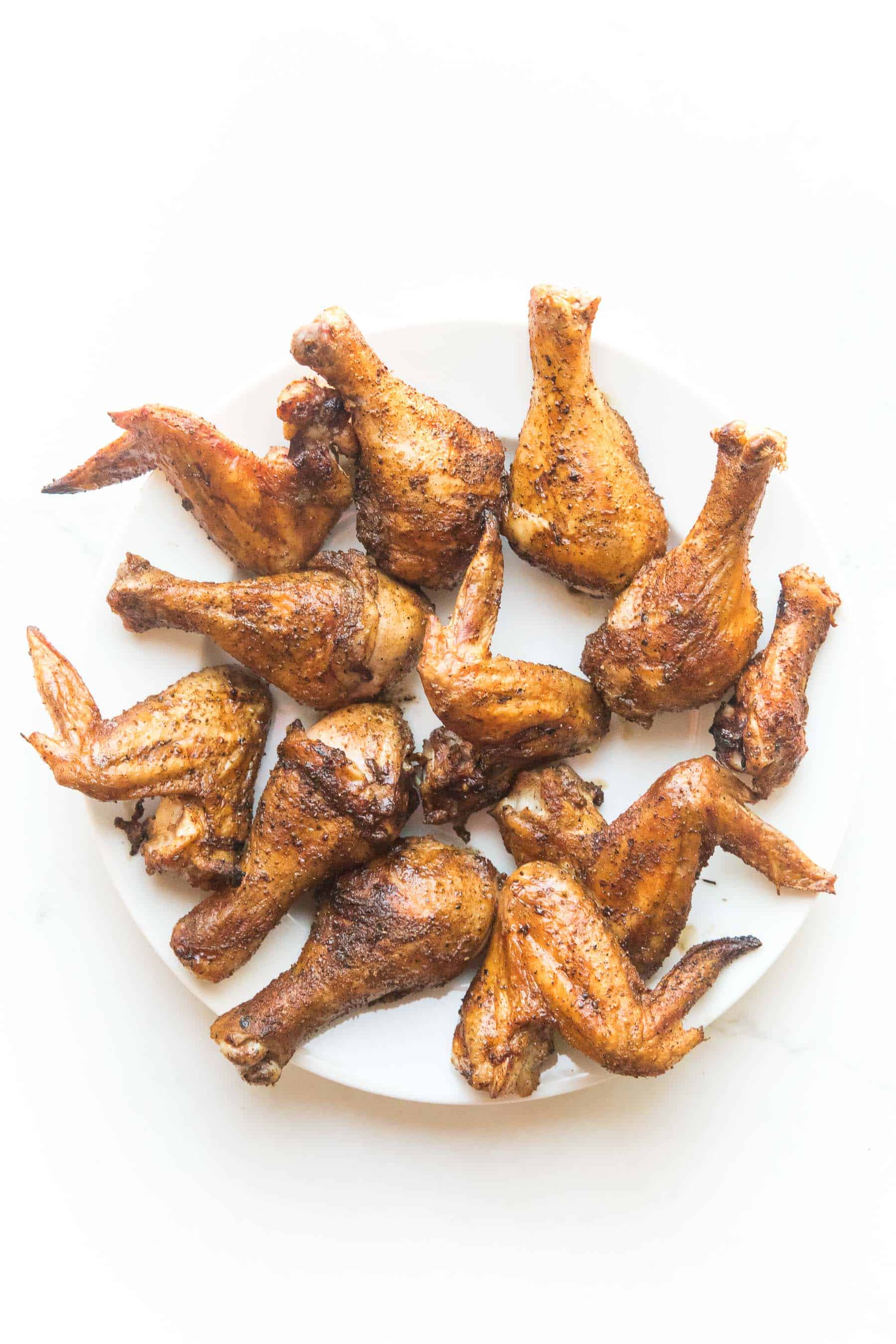 crispy roasted drumsticks + wings on a white plate and background