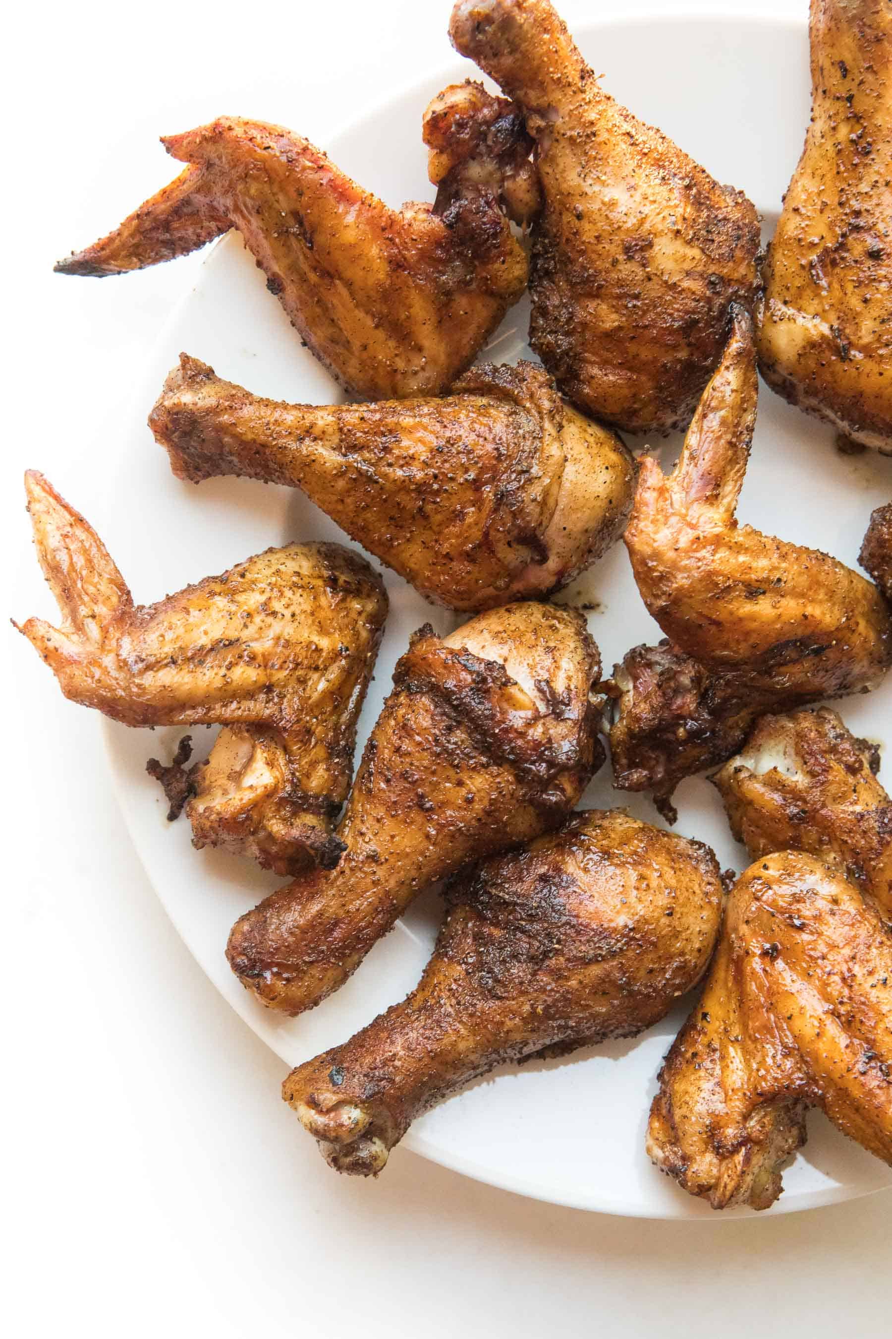 crispy roasted drumsticks + wings on a white plate and background