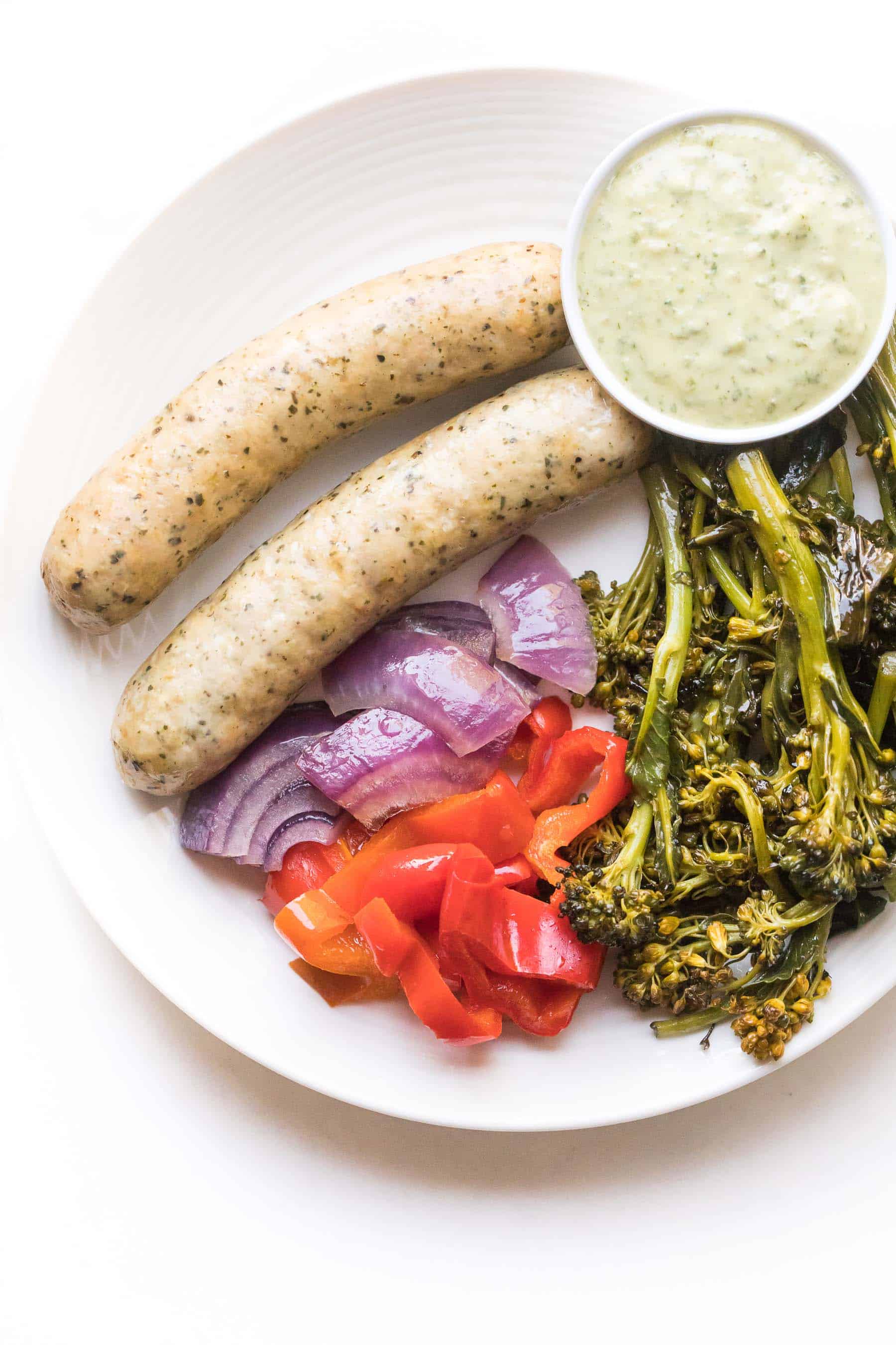 sausages and vegetables on a white plate on a white background