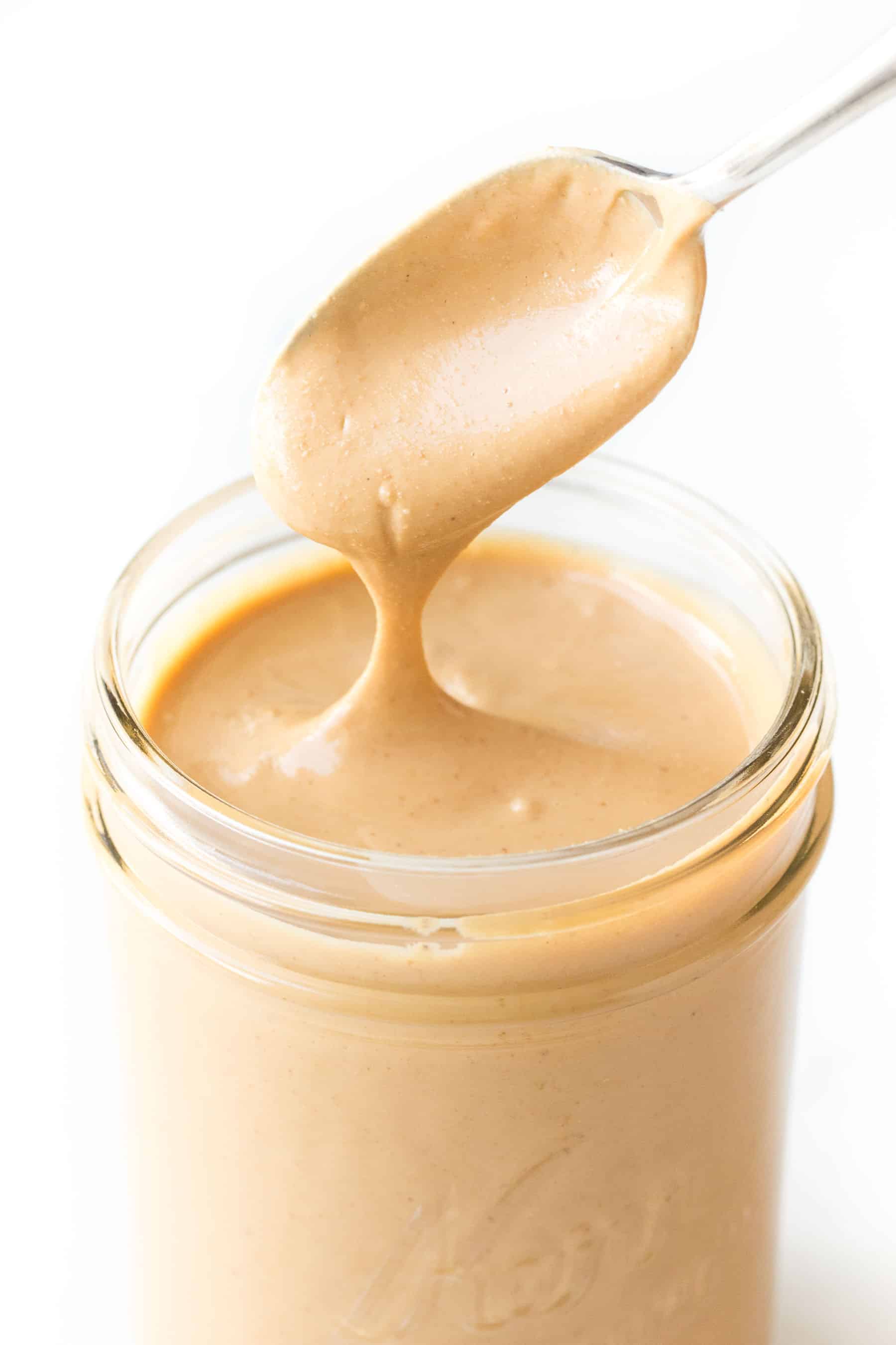 spoon pouring cashew butter into a mason jar