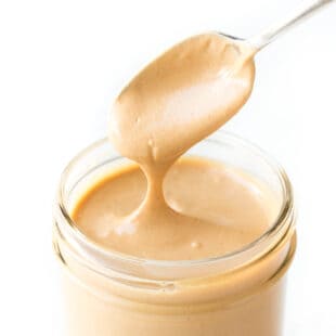 spoon pouring cashew butter into a mason jar