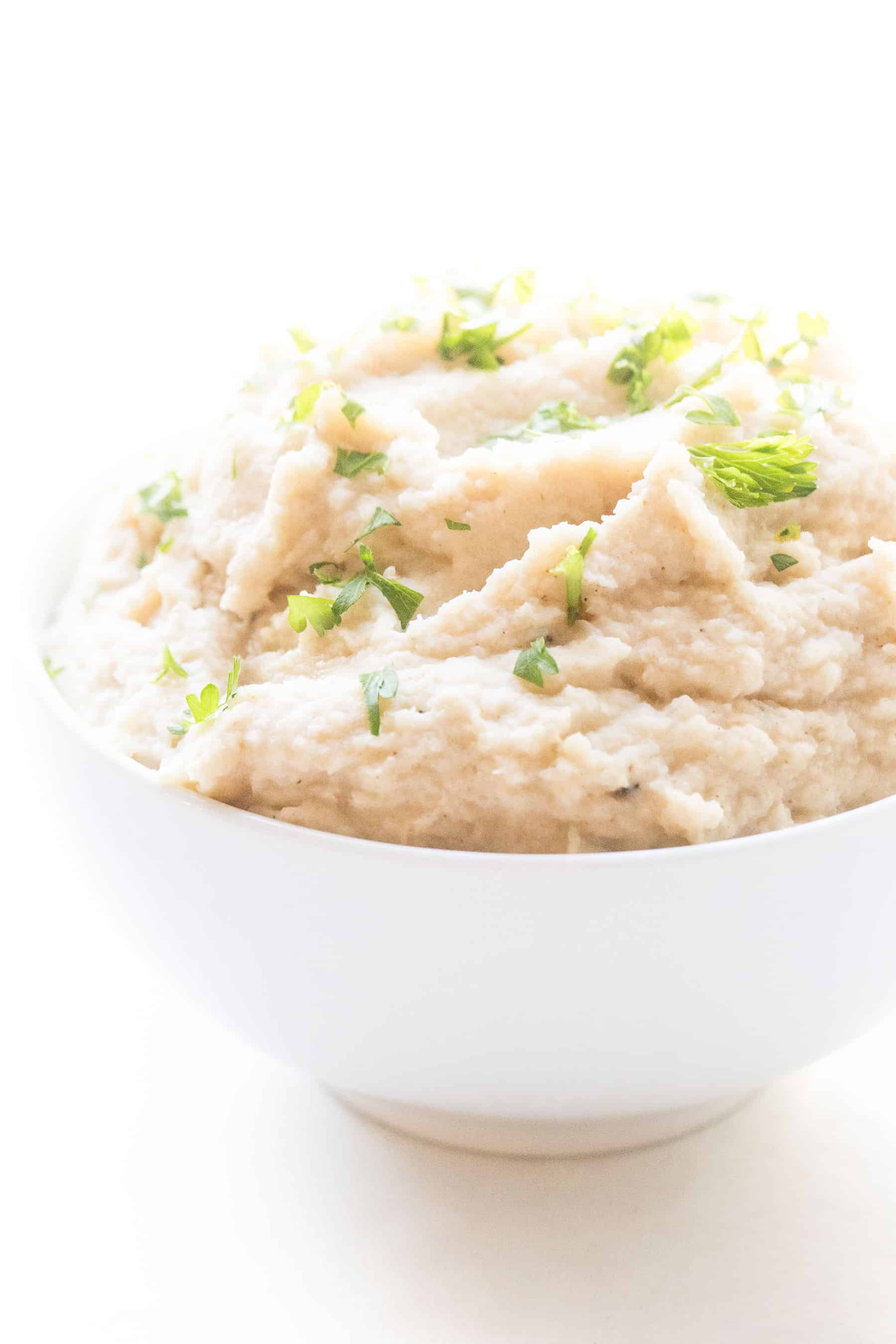 creamy mashed cauliflower in a white bowl and background