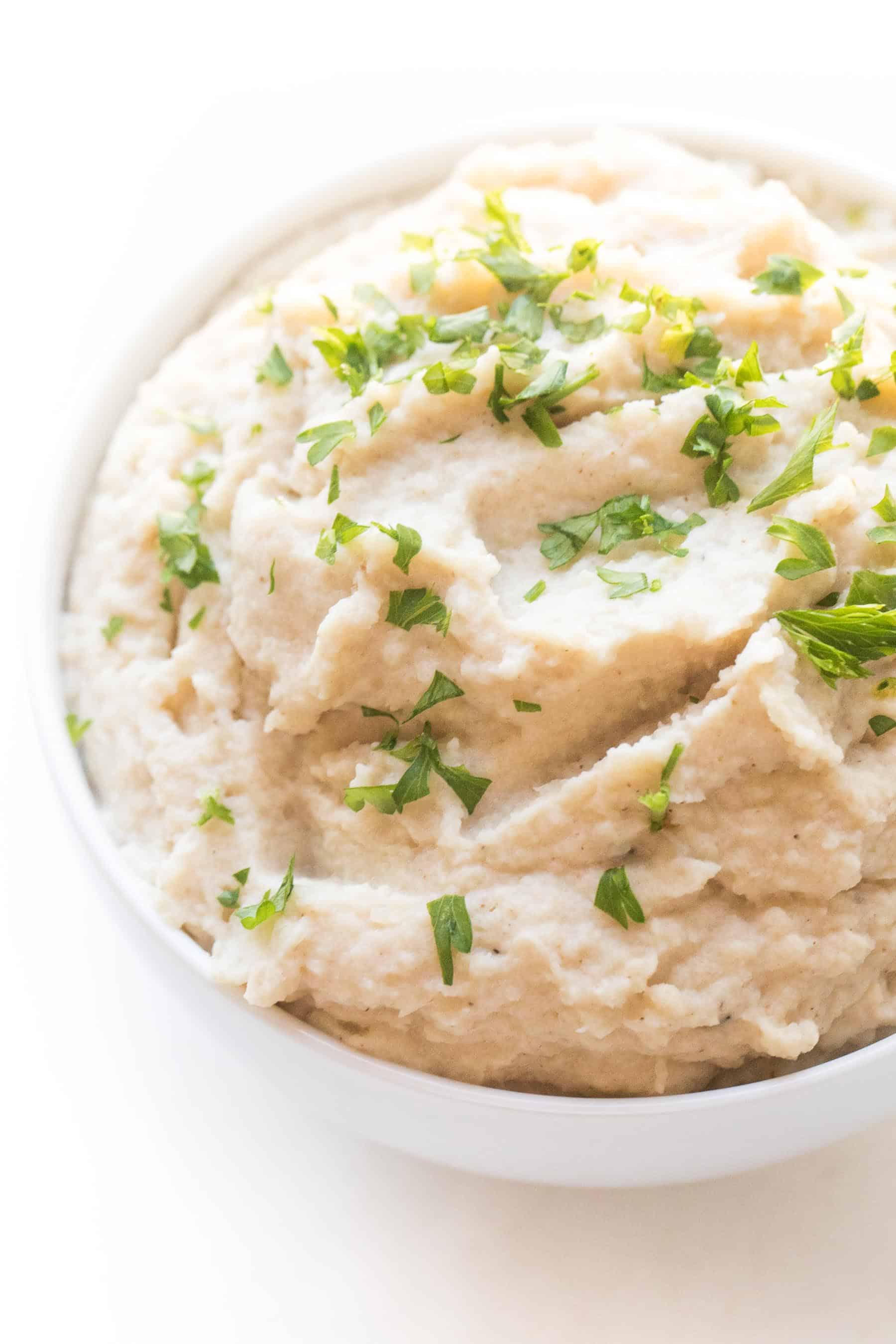 creamy mashed cauliflower in a white bowl and background