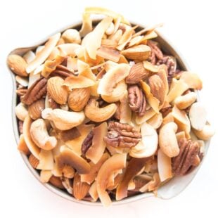 nuts and coconut chips trail mix in a bowl on white background