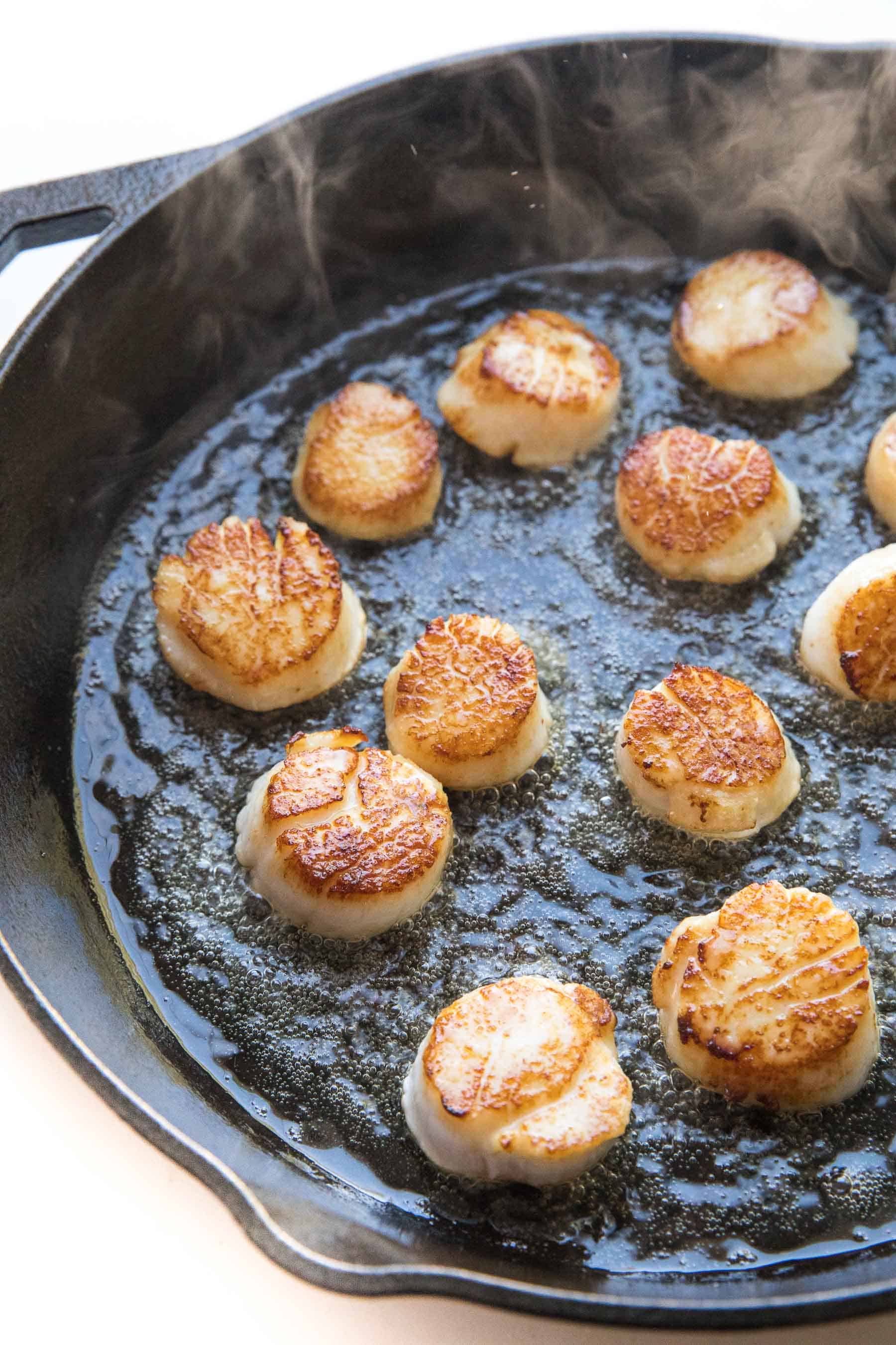 scallops searing in a cast iron skillet