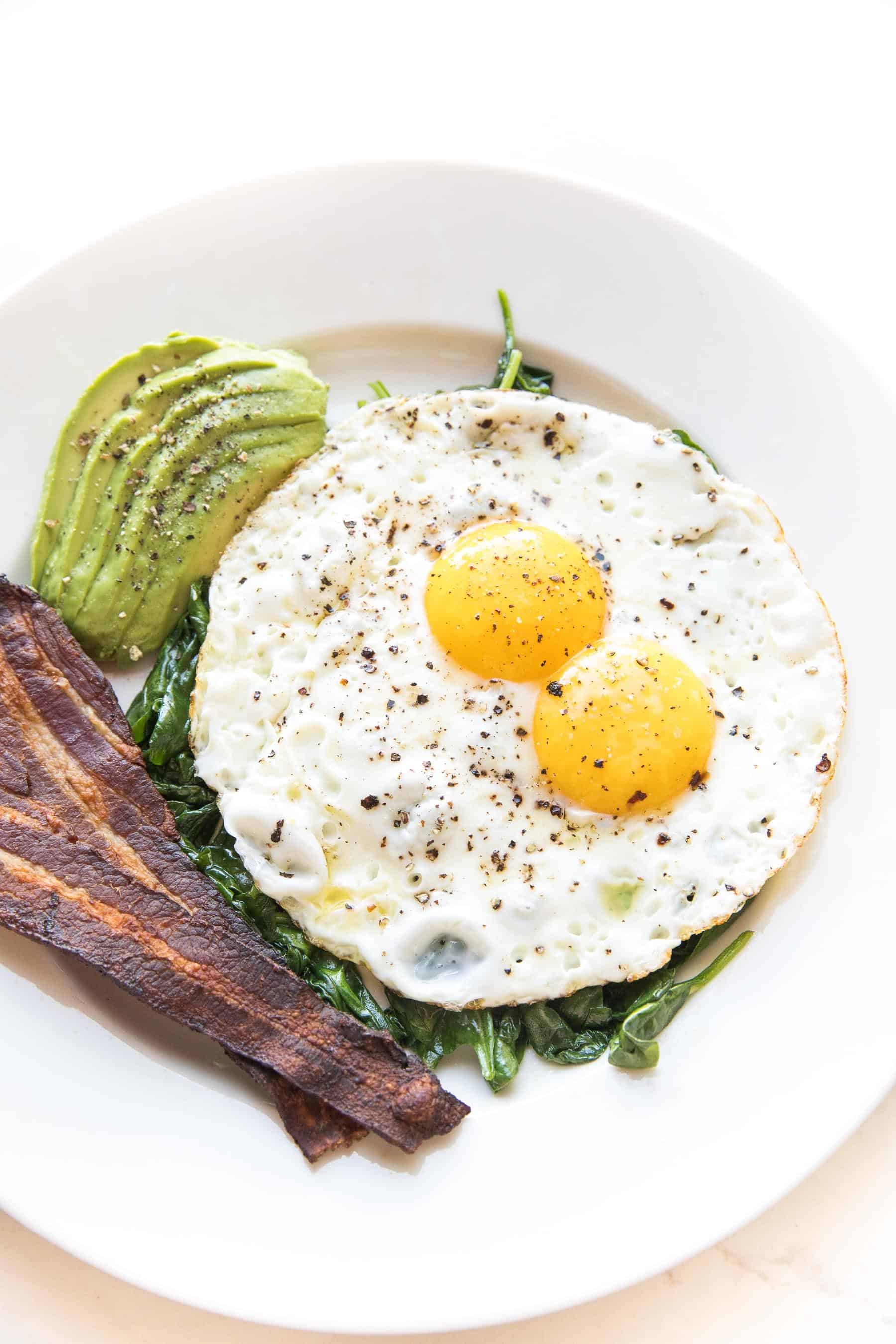 sunny side up eggs with sauteed spinach, bacon + avocado