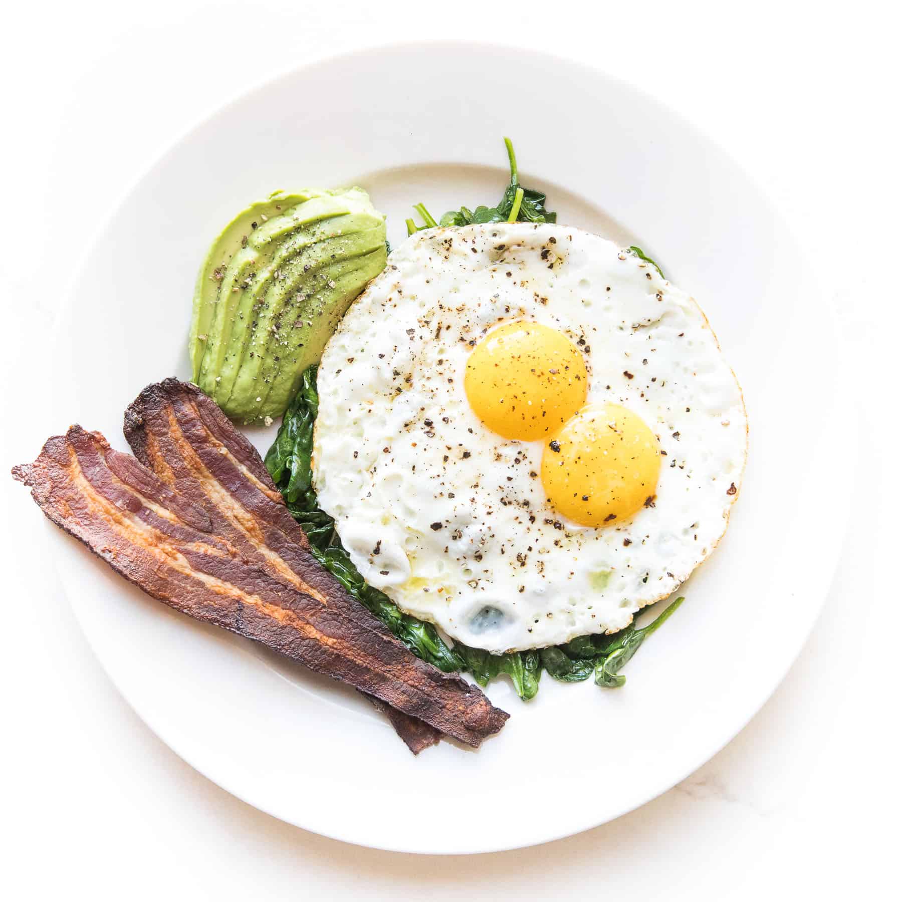 sunny side up eggs with sauteed spinach, bacon + avocado