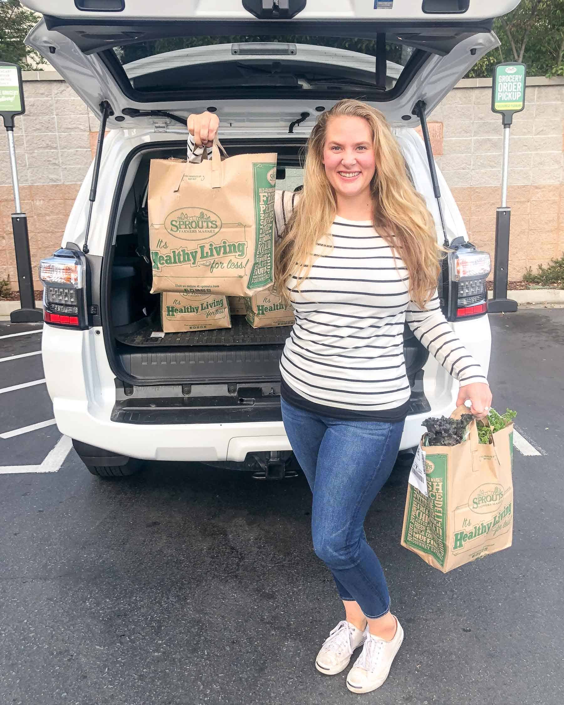 girl holding sprouts grocery delivery by a car