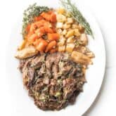 pot roast on a white plate with fresh herbs